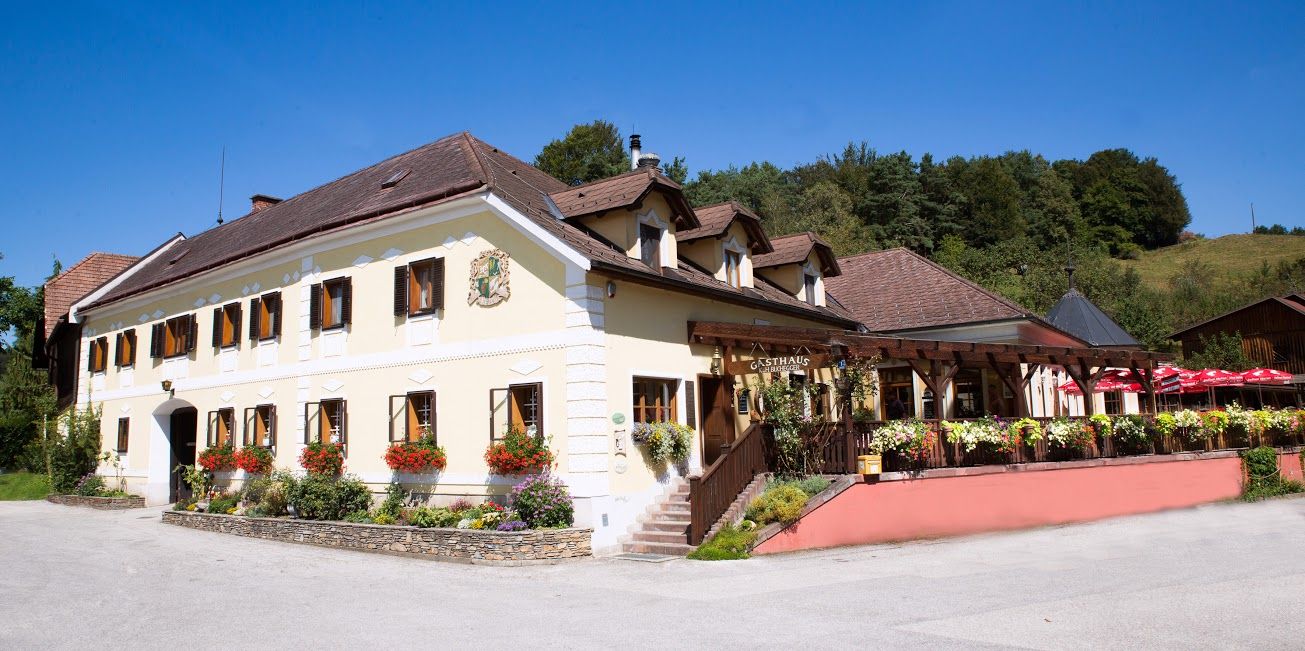Traditional inn with yellow facade, many windows and terrace.