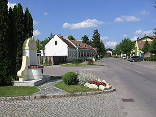 Street in Mitterndorf an der Fischa with houses and monument.