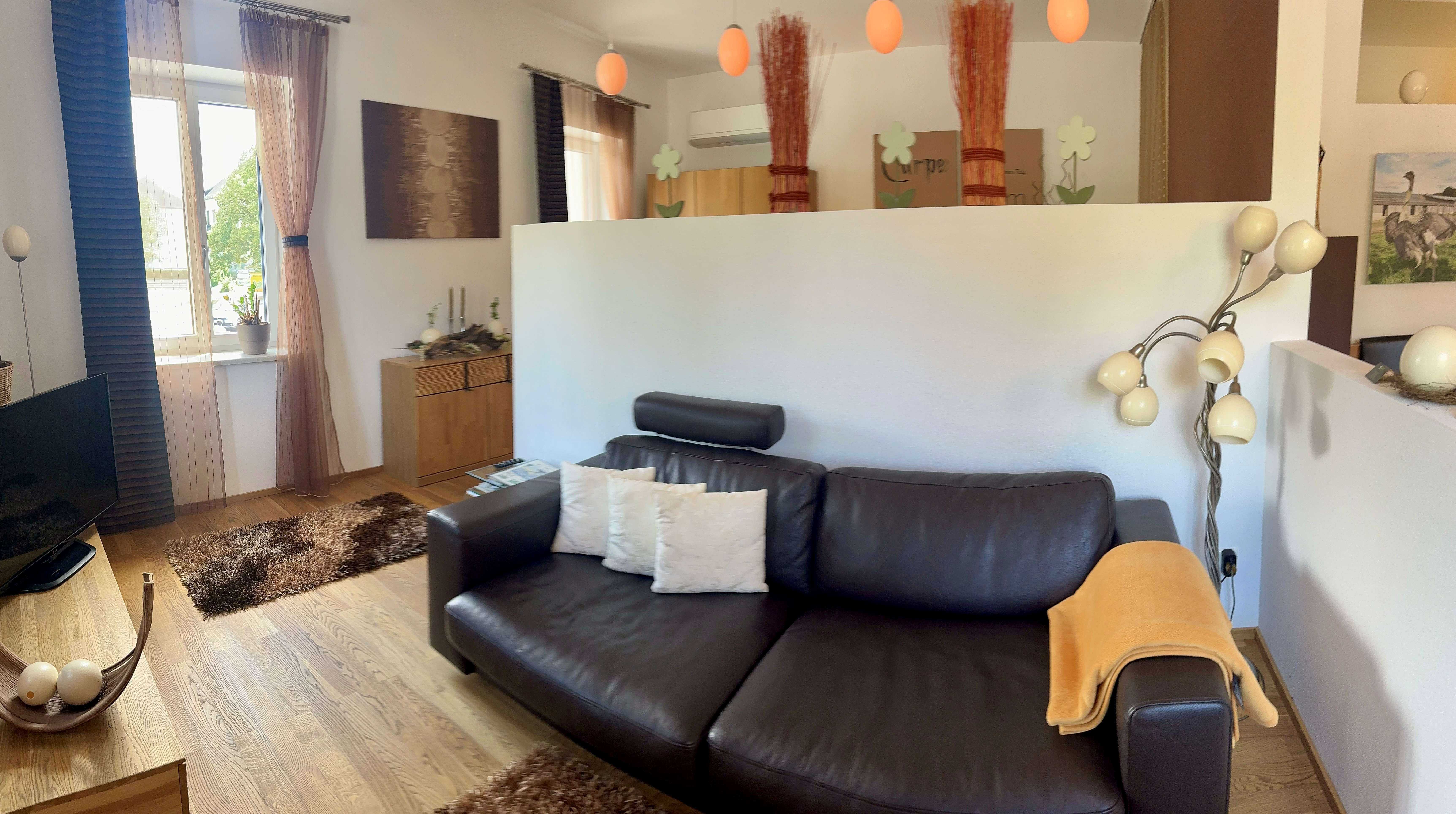 A modern living room with a leather sofa, a floor lamp, and decorative accents.