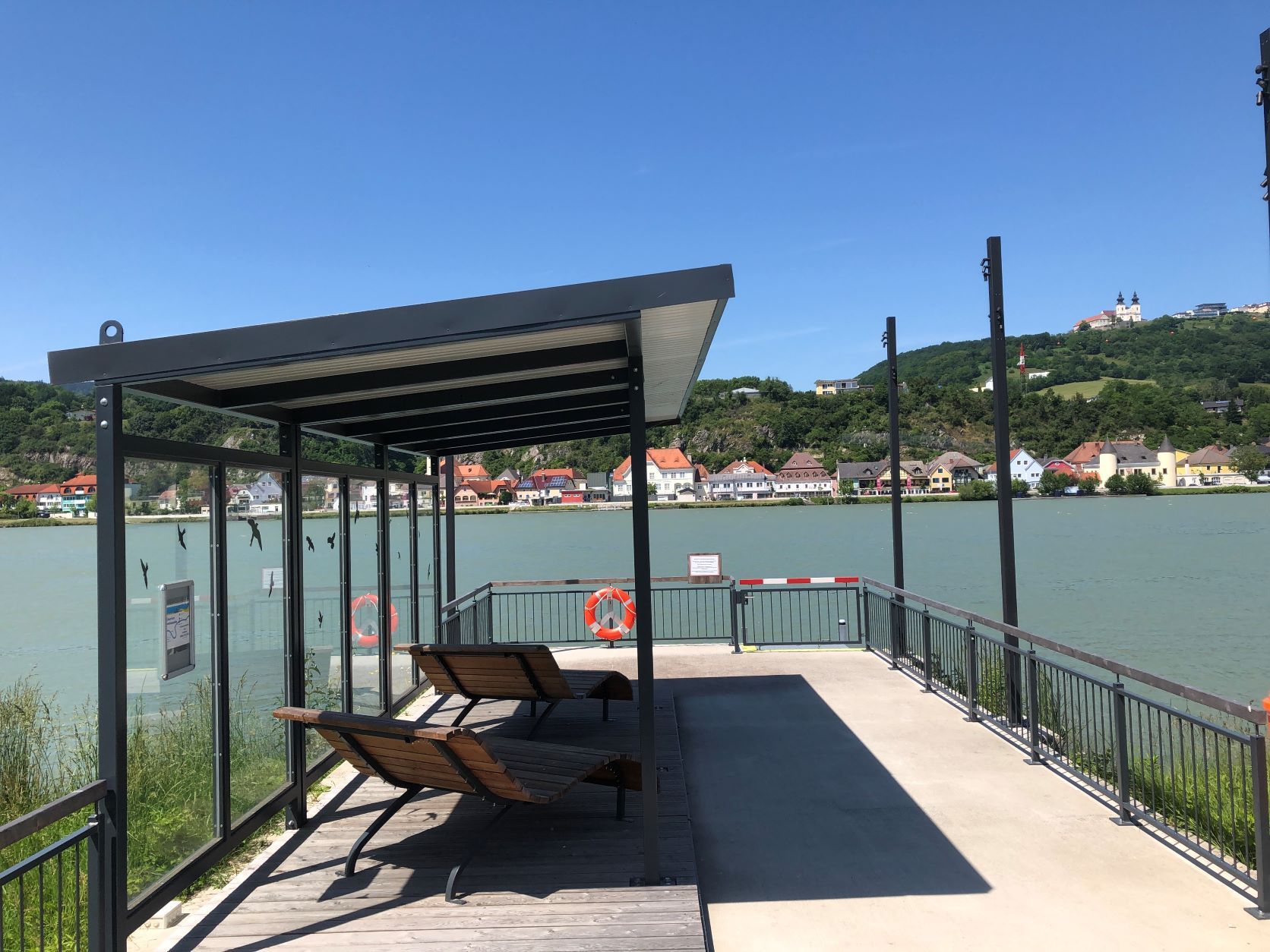 Mooring with canopy and loungers, river in the background, basilica on a hill.