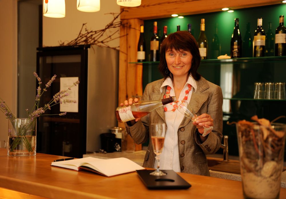 Woman pouring wine into a glass at a bar.