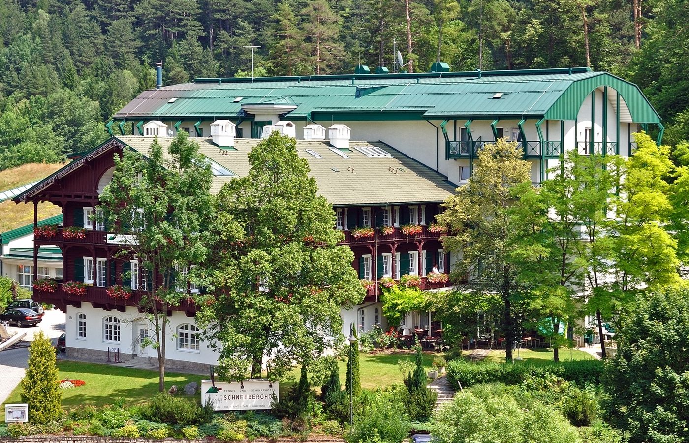 A large hotel building with green roofs and balconies, surrounded by trees and nature.