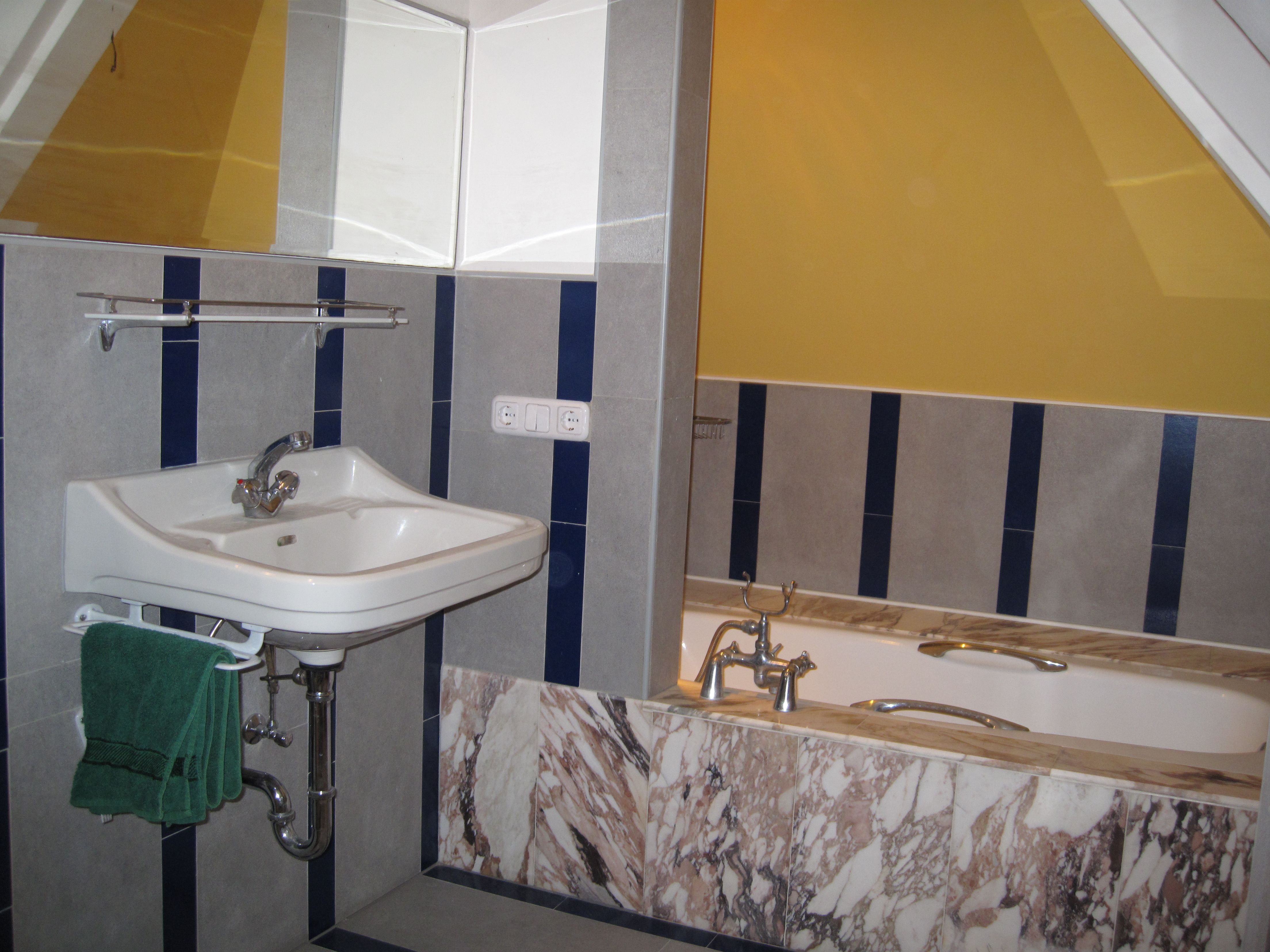 Bathroom with washbasin, bathtub and yellow wall.