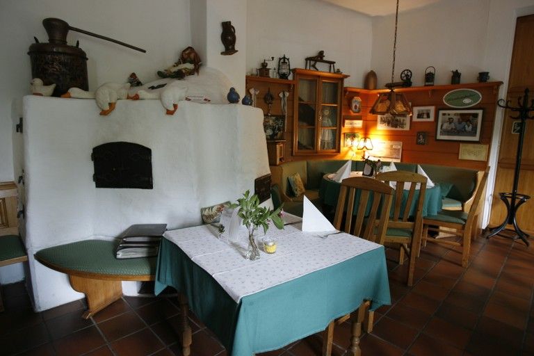 Cozy inn with rustic furnishings, wooden furniture and tiled stove.