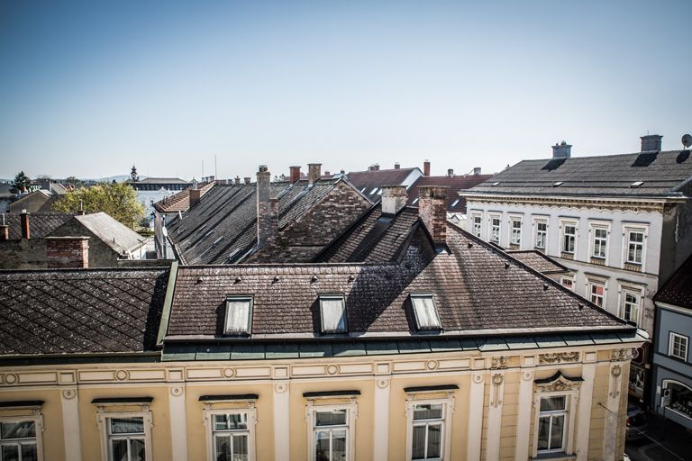 View of the roofs of the neighboring buildings and blue sky.