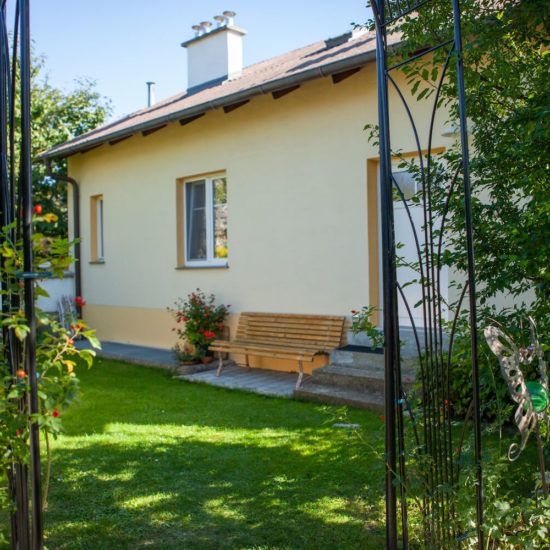 A yellow house with a garden bench and flowers in the foreground.