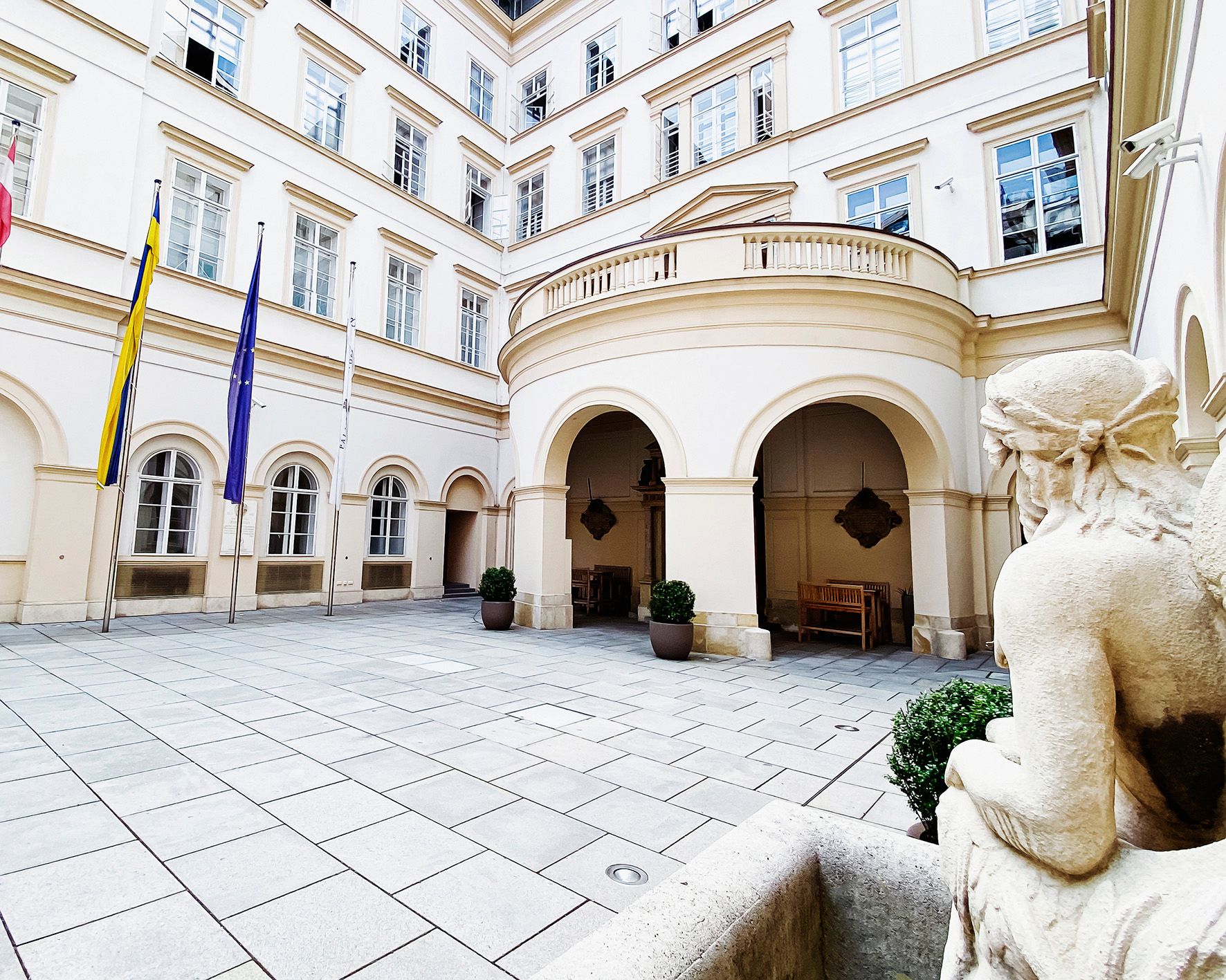 Inner courtyard of Palais Niederösterreich with flags and statue.