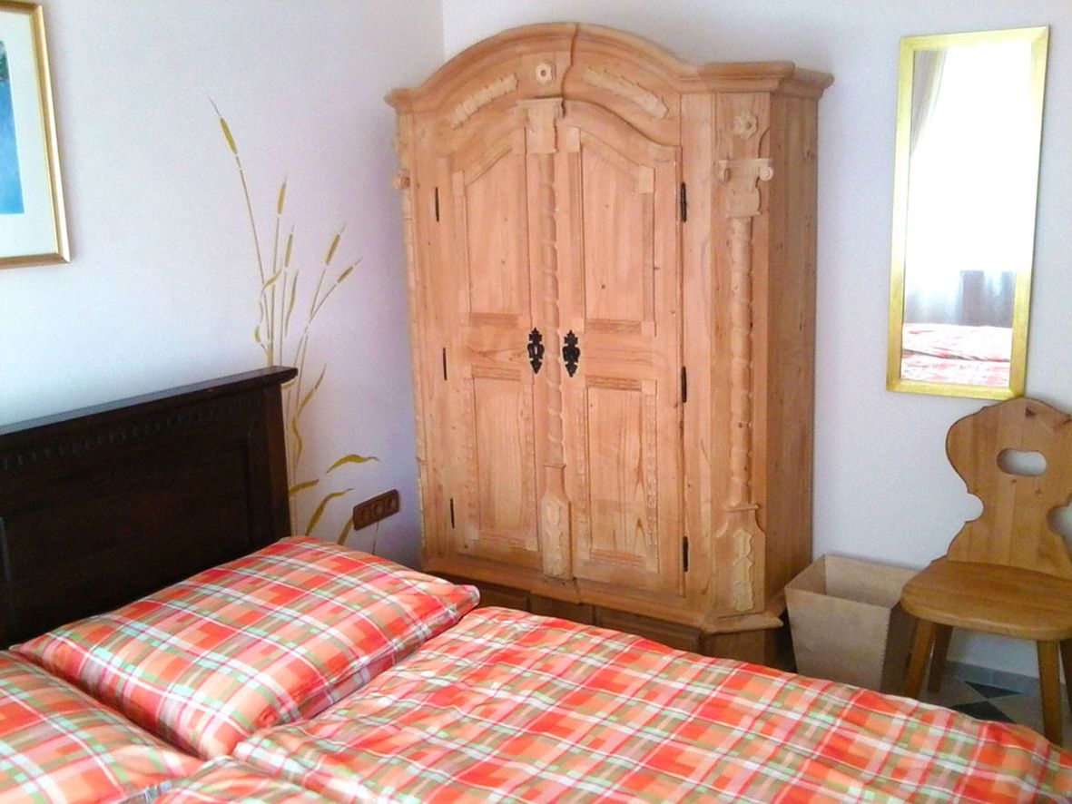 Guest room with wooden furniture and checkered comforter cover.