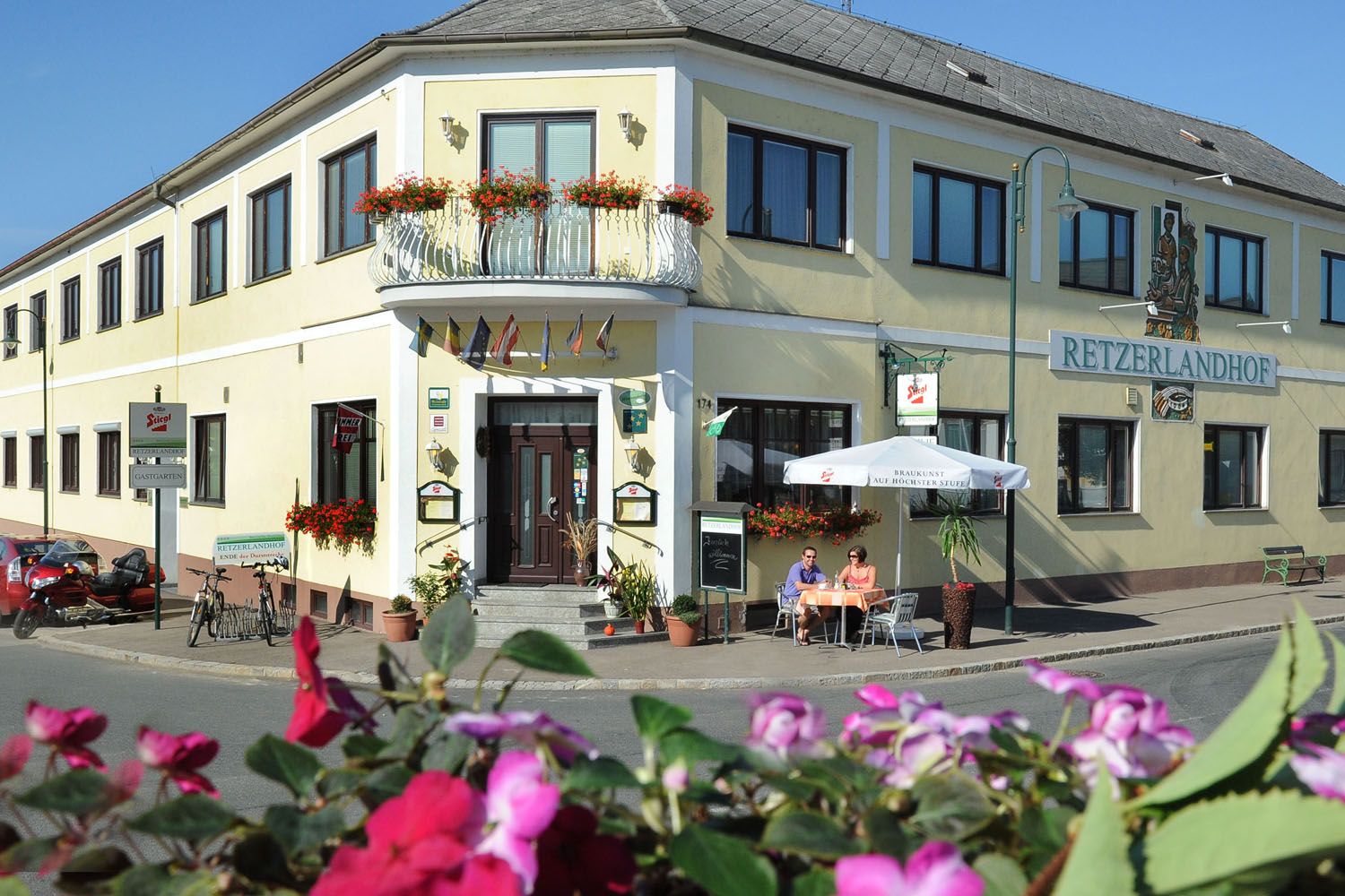 Exterior view of the Retzerlandhof with terrace and flowers.