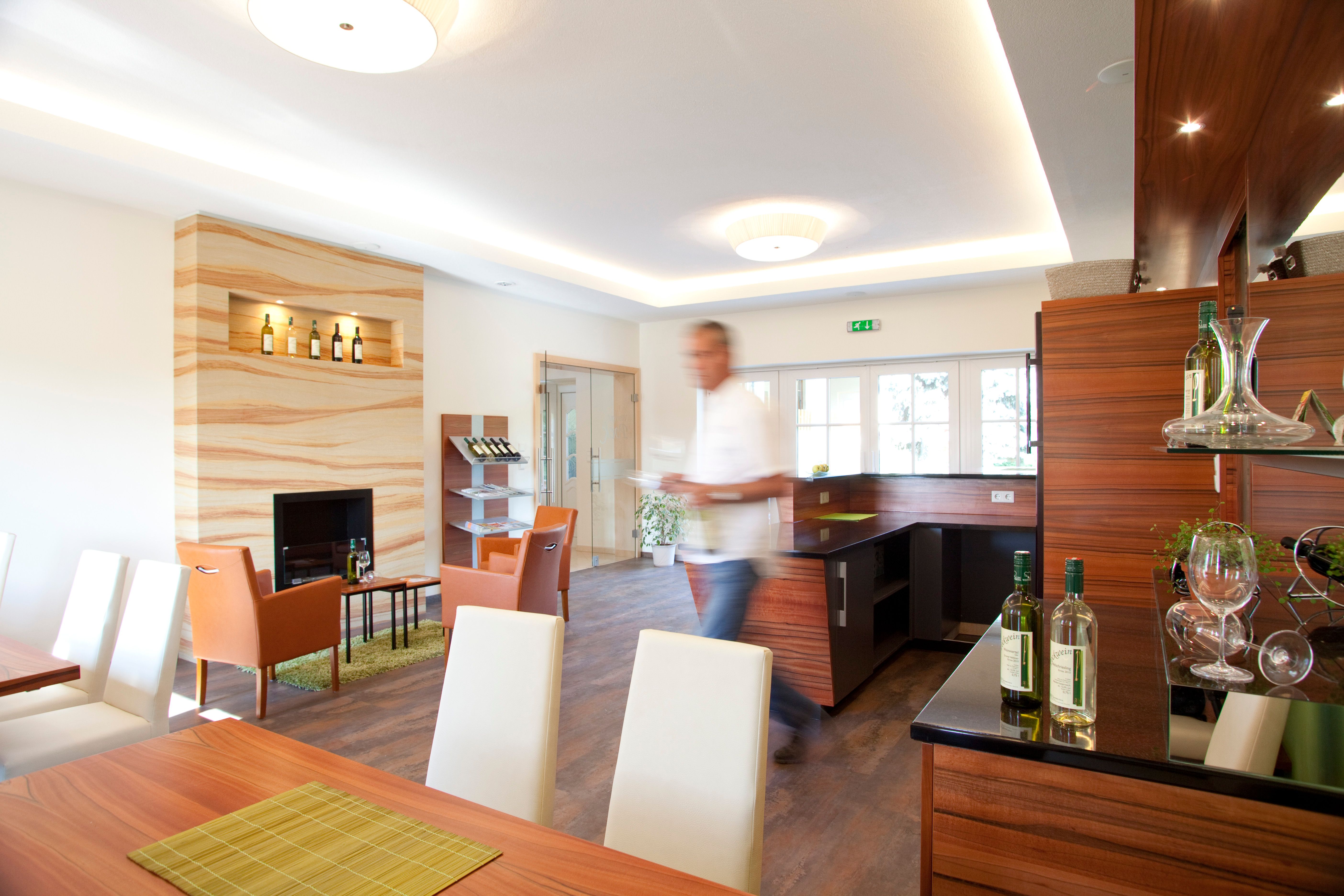 A modern tasting room with wooden furniture, bottles of wine and a blurred man in the foreground.