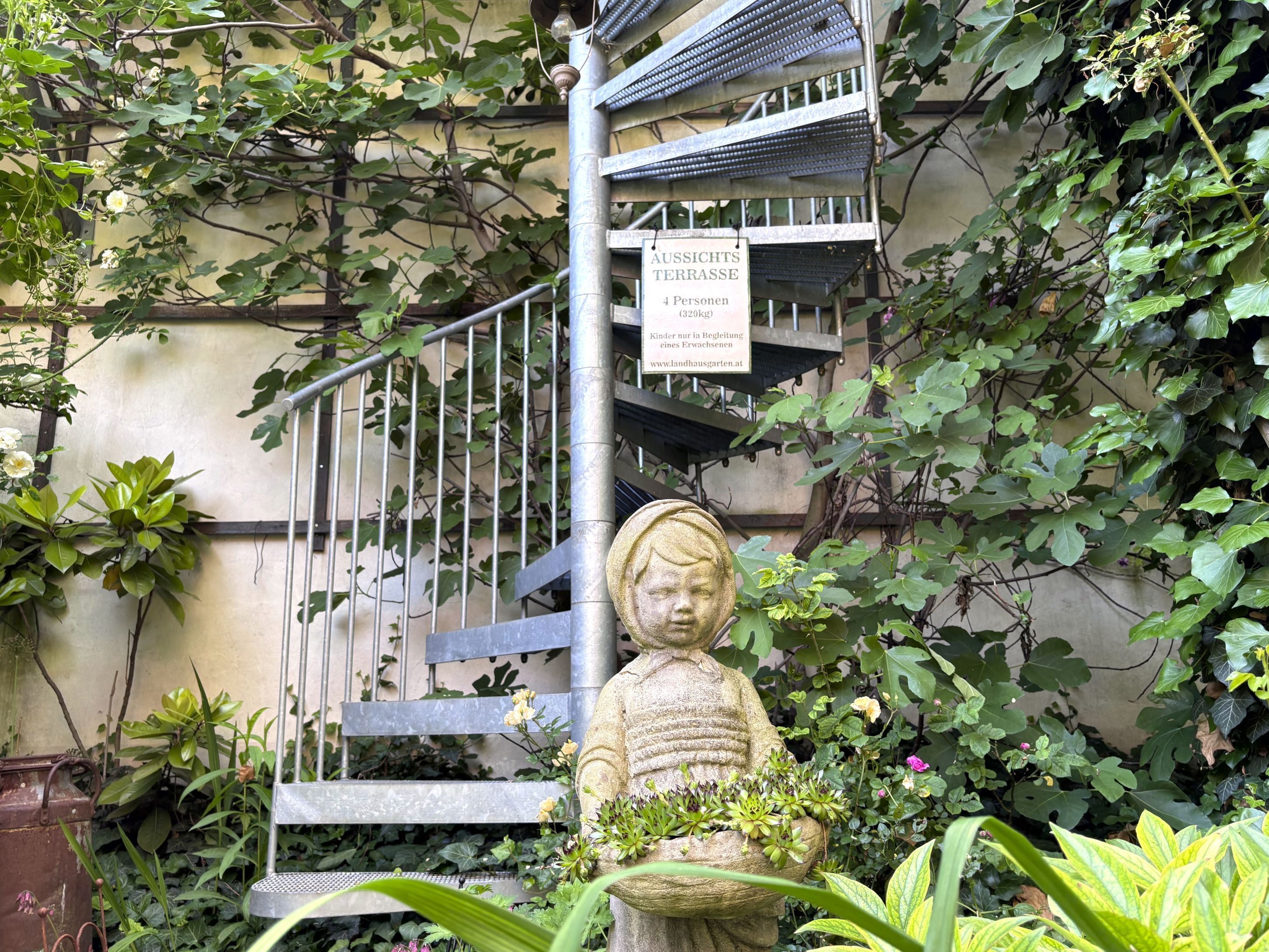 Stone steps in the garden with plants and a statue of a child.