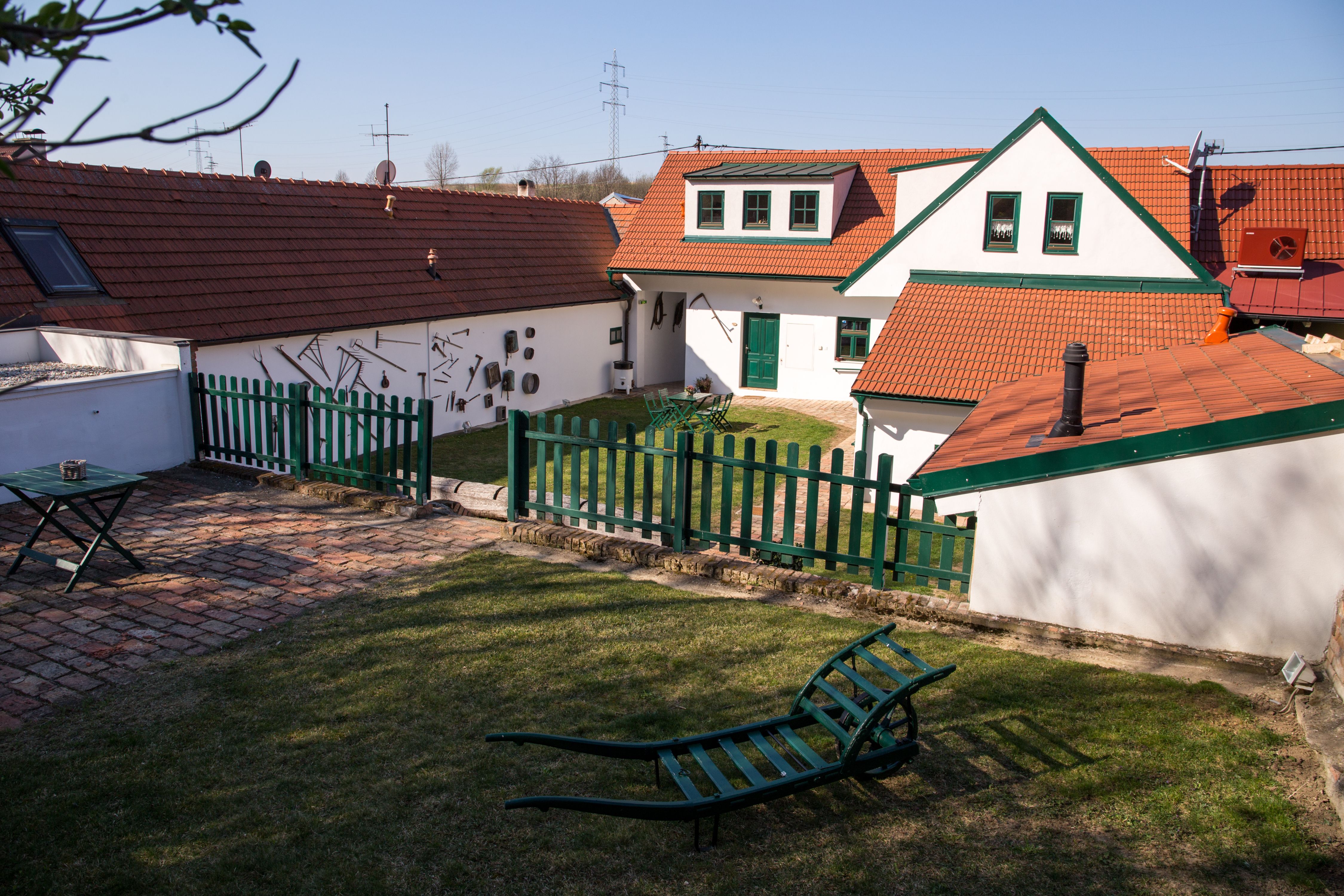 A traditional vineyard with red tiled roofs, green fences and garden furniture on a meadow.