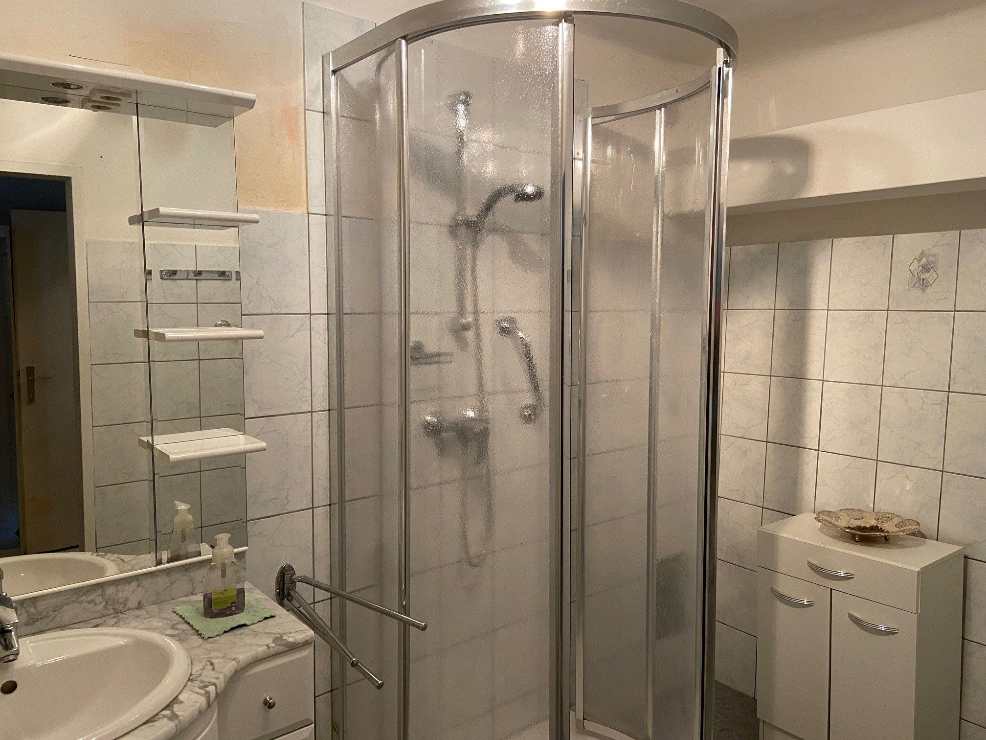 Bathroom with shower, washbasin and mirror.