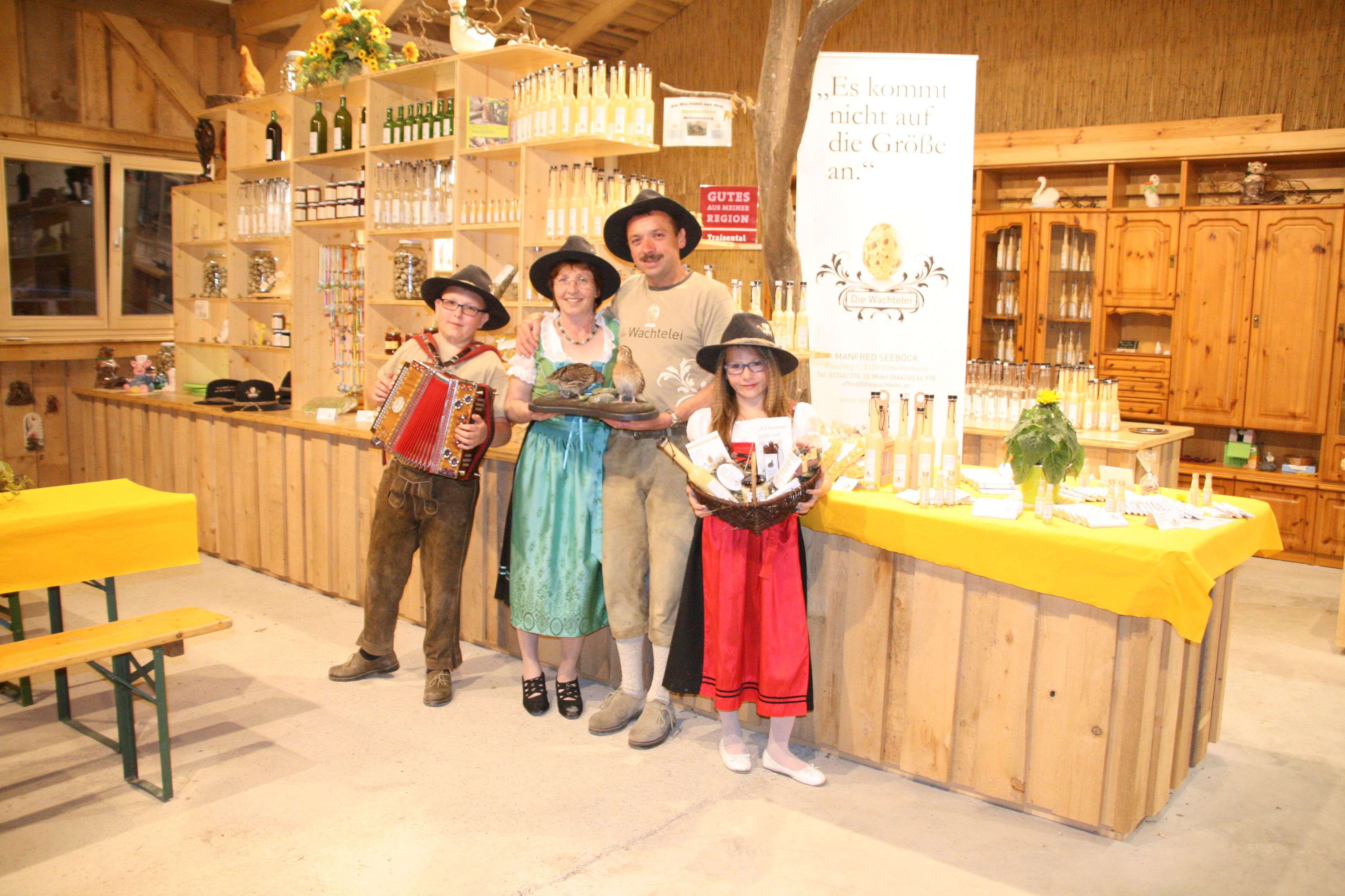 A family in traditional dress stands in a store with products and a banner reading 'The Quail's Egg'.