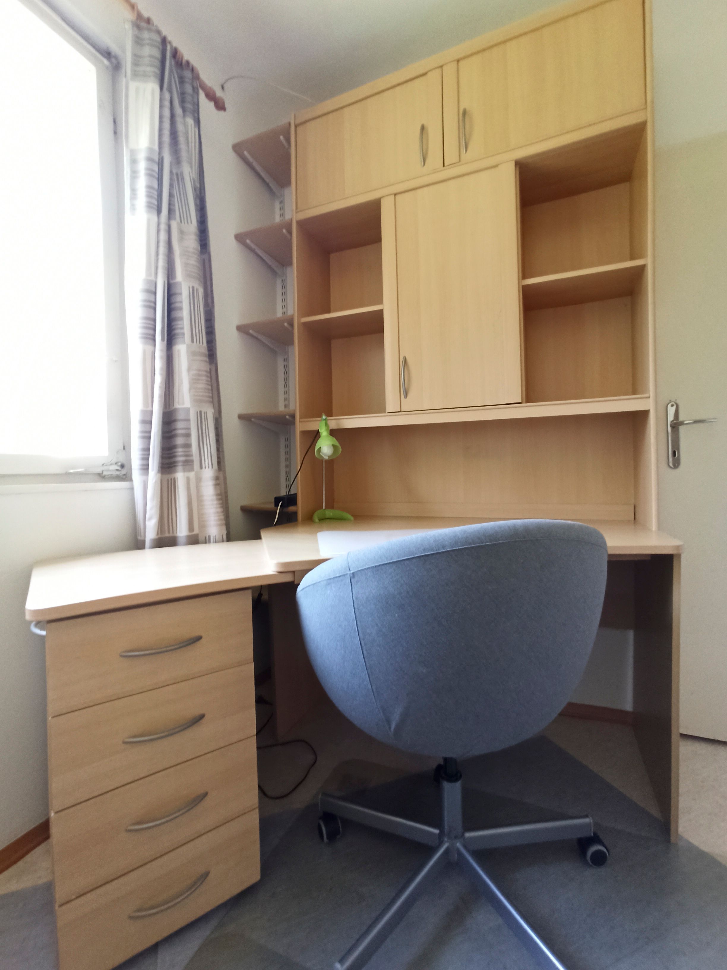 A modern desk with a gray office chair and a shelf with drawers and compartments.