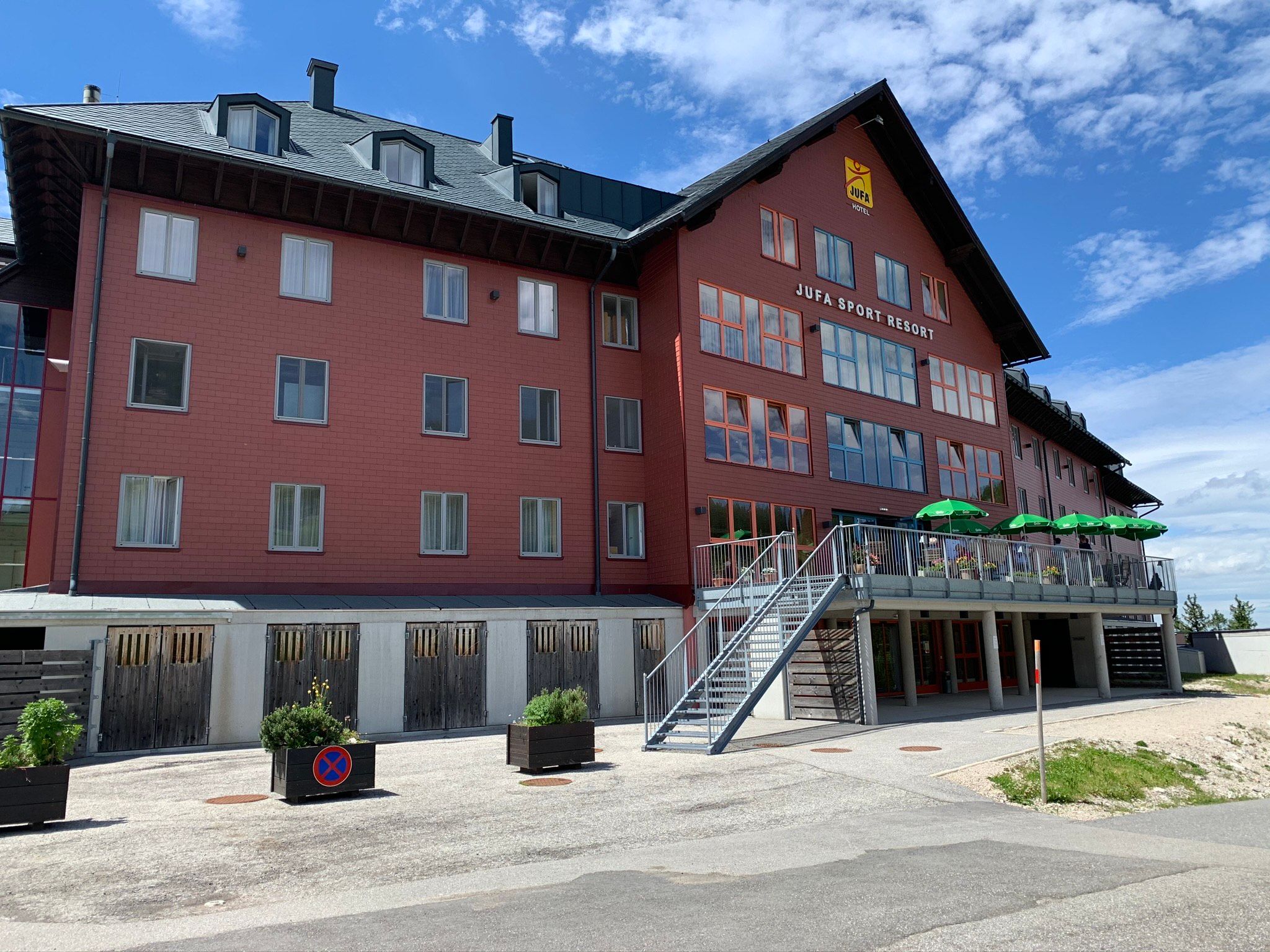 JUFA Sport Resort Hochkar with red facade and terrace with green sunshades.