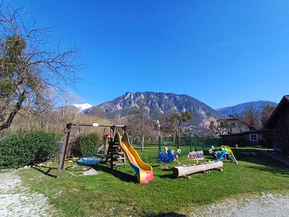 Children's playground with slide and swings against a mountain backdrop.