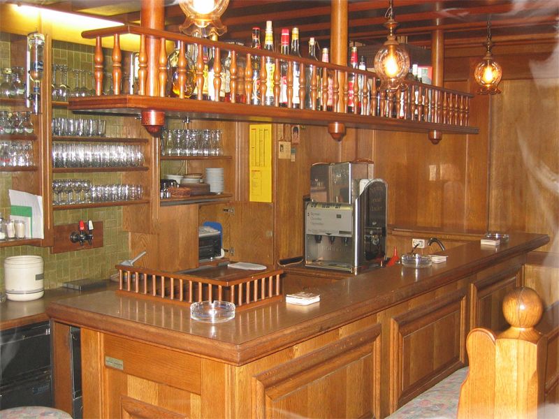 Interior view of a traditional bar with wooden furnishings and glasses.