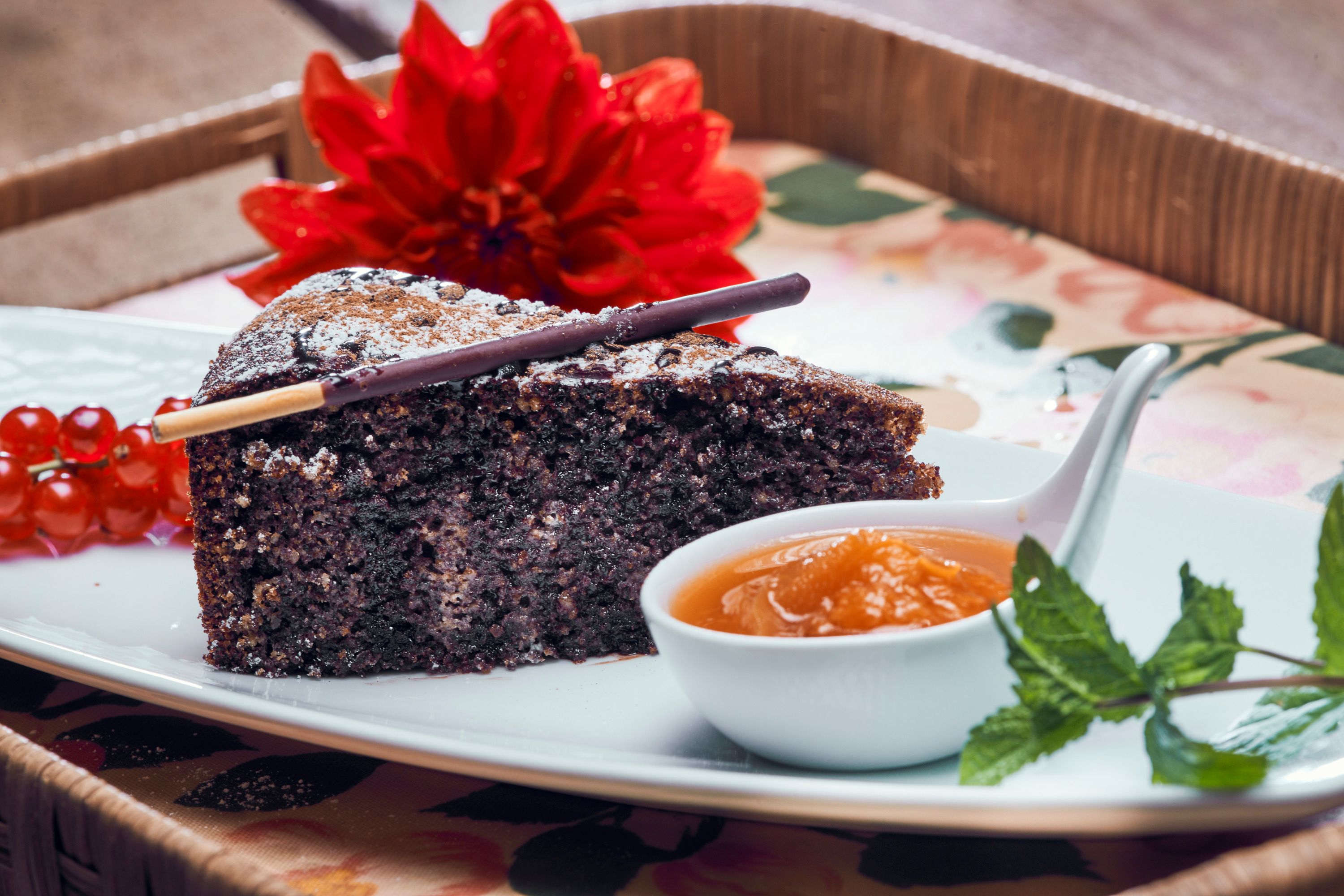 Poppy seed cake with powdered sugar, berries and apricot jam on a plate.