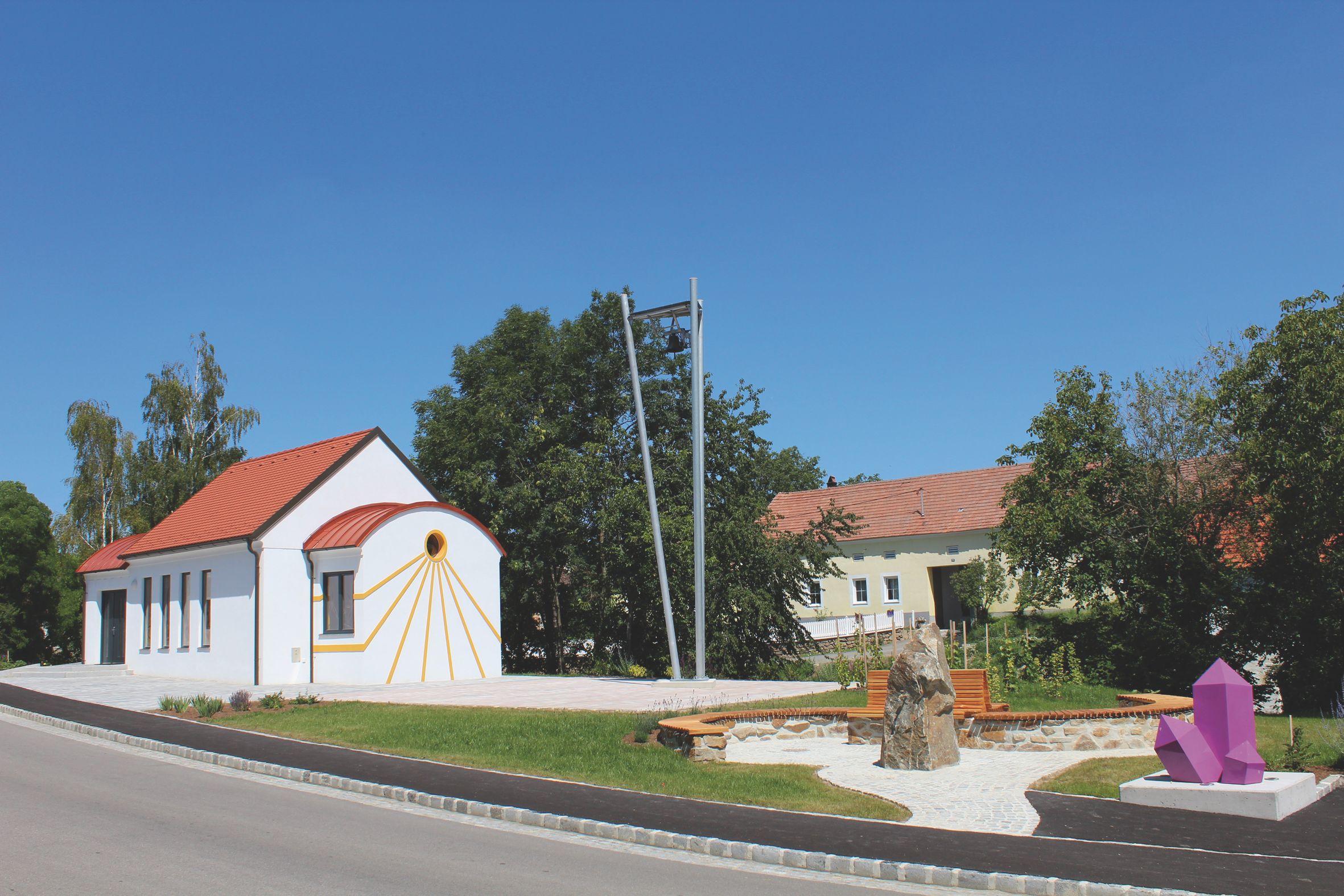 White chapel with red roof and amethyst sculpture in the foreground.
