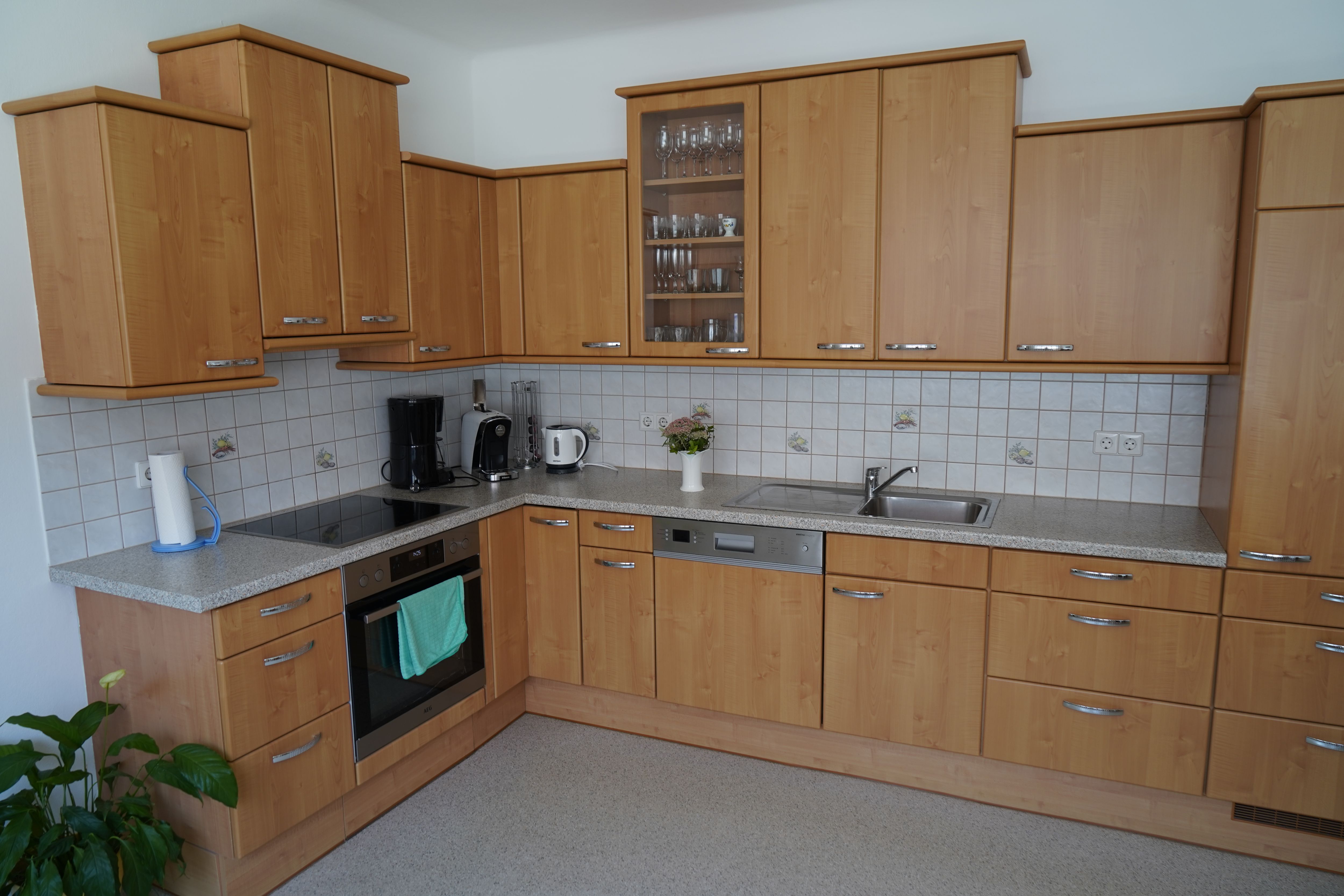 Modern kitchen with wooden cupboards, electrical appliances and sink.