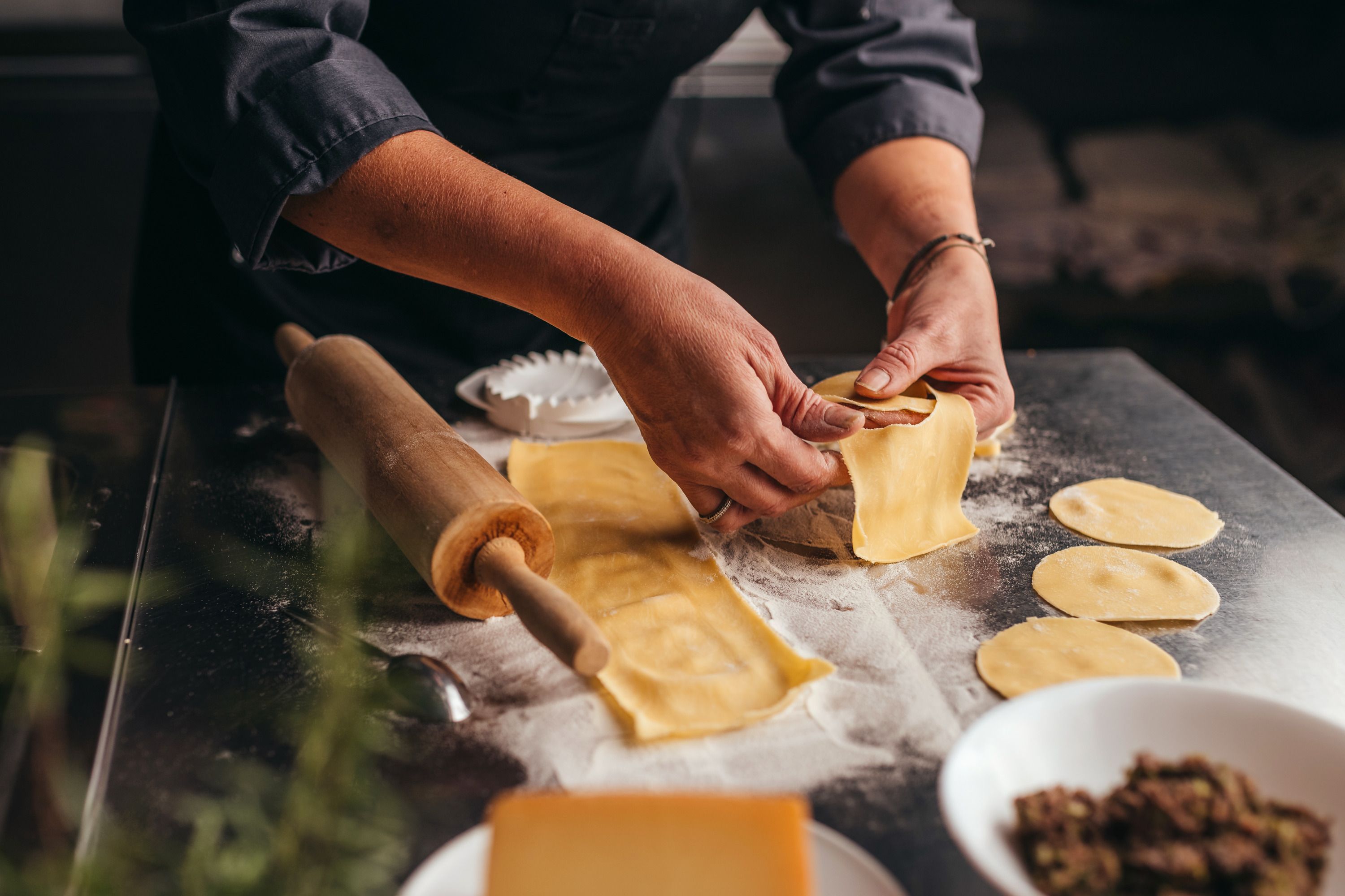 Person forms dumplings on a floured work surface.
