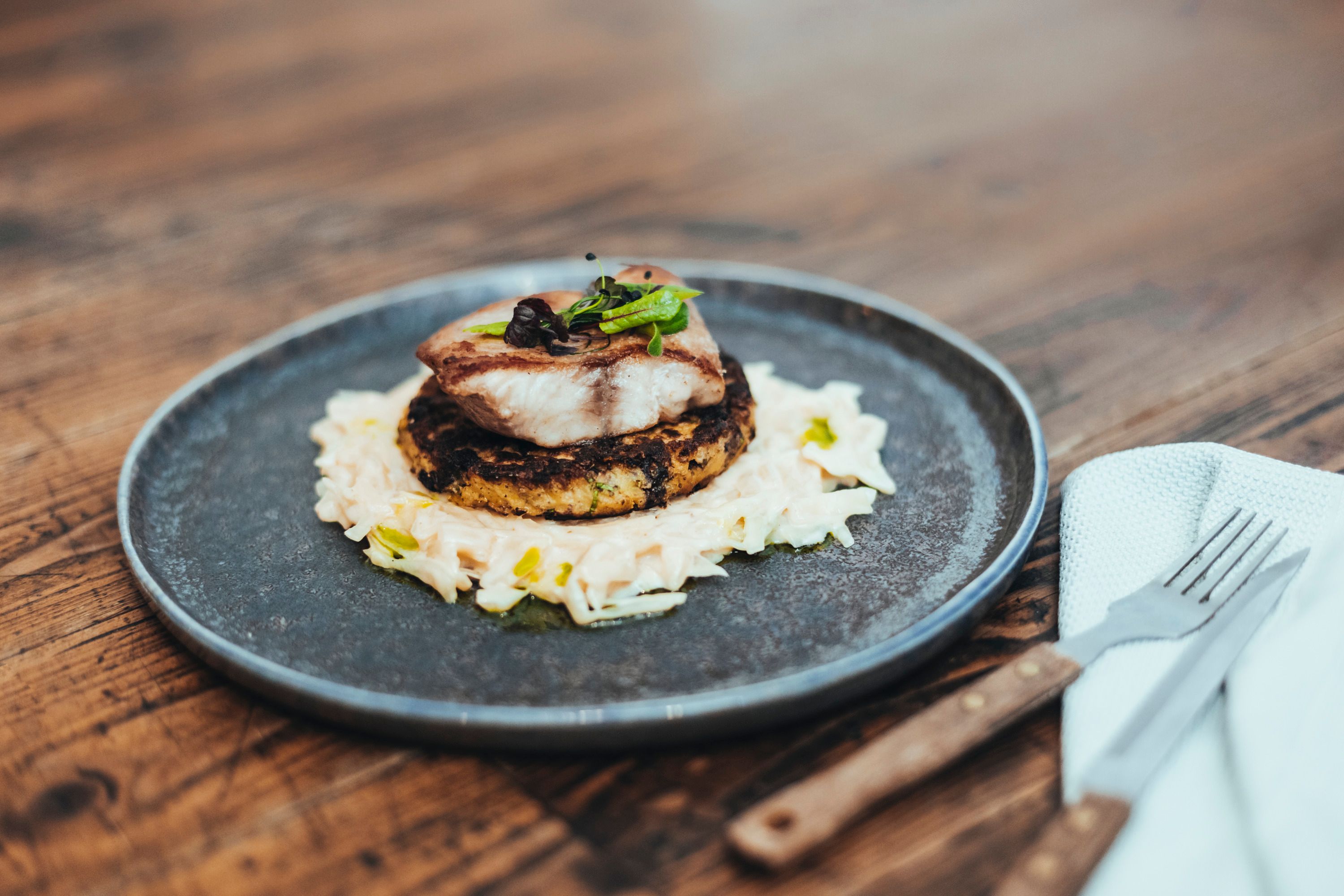 A dish with fish on rösti and cabbage on a plate.