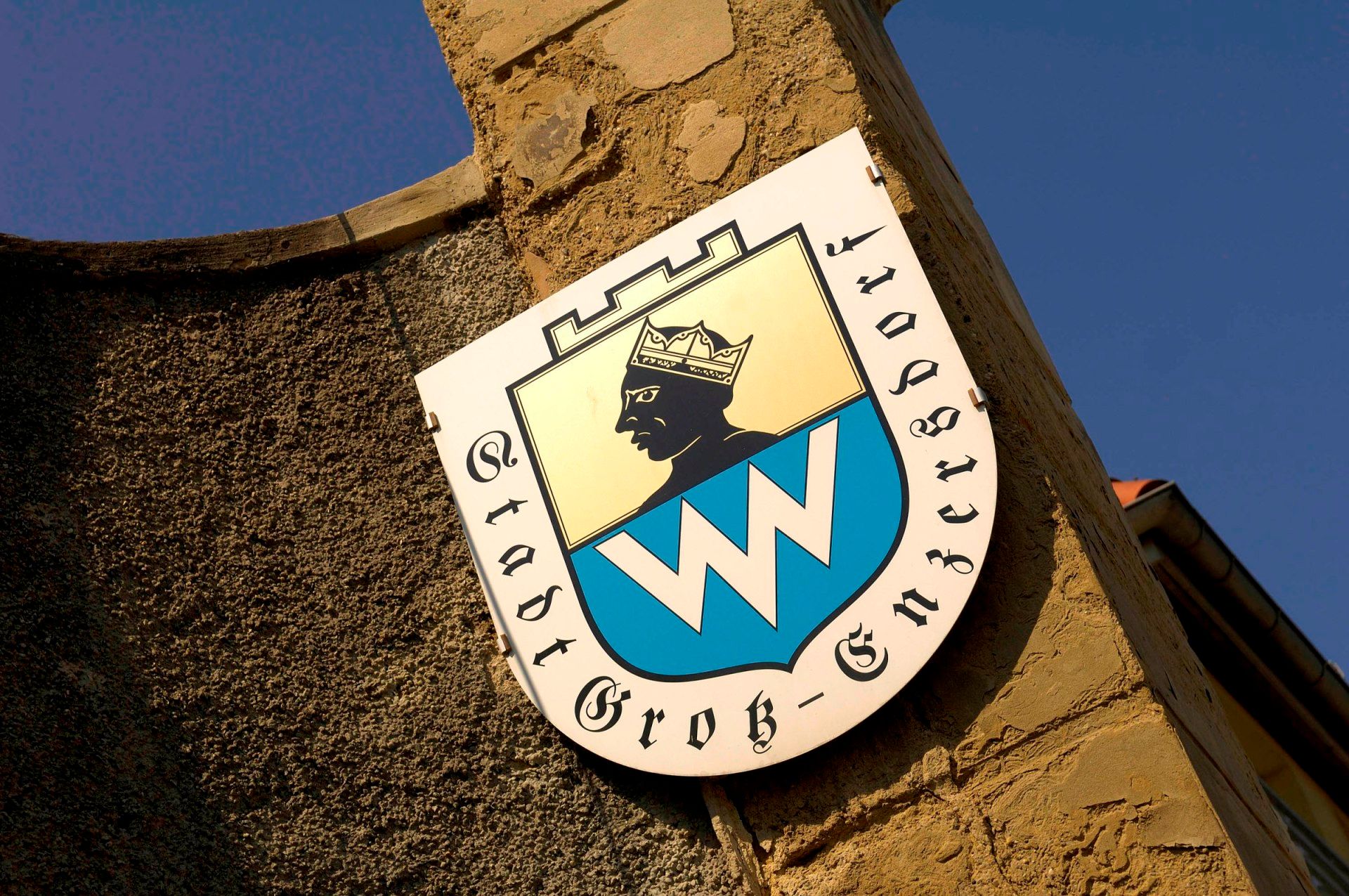 Coat of arms of the municipality of Groß-Enzersdorf on a stone wall.