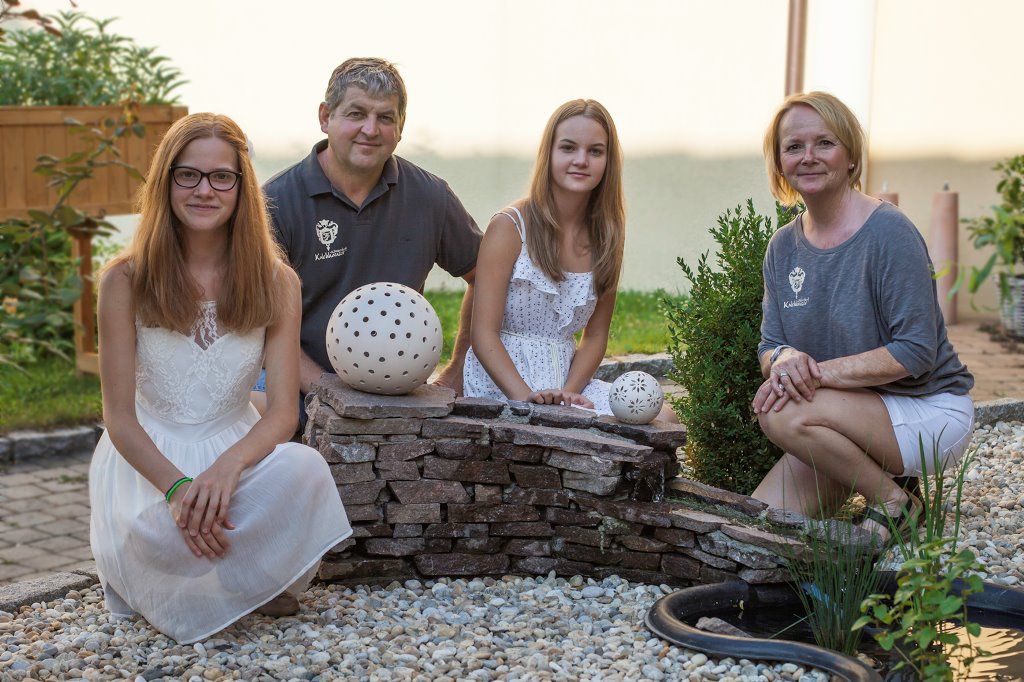 Four people pose in the garden next to a small fountain.