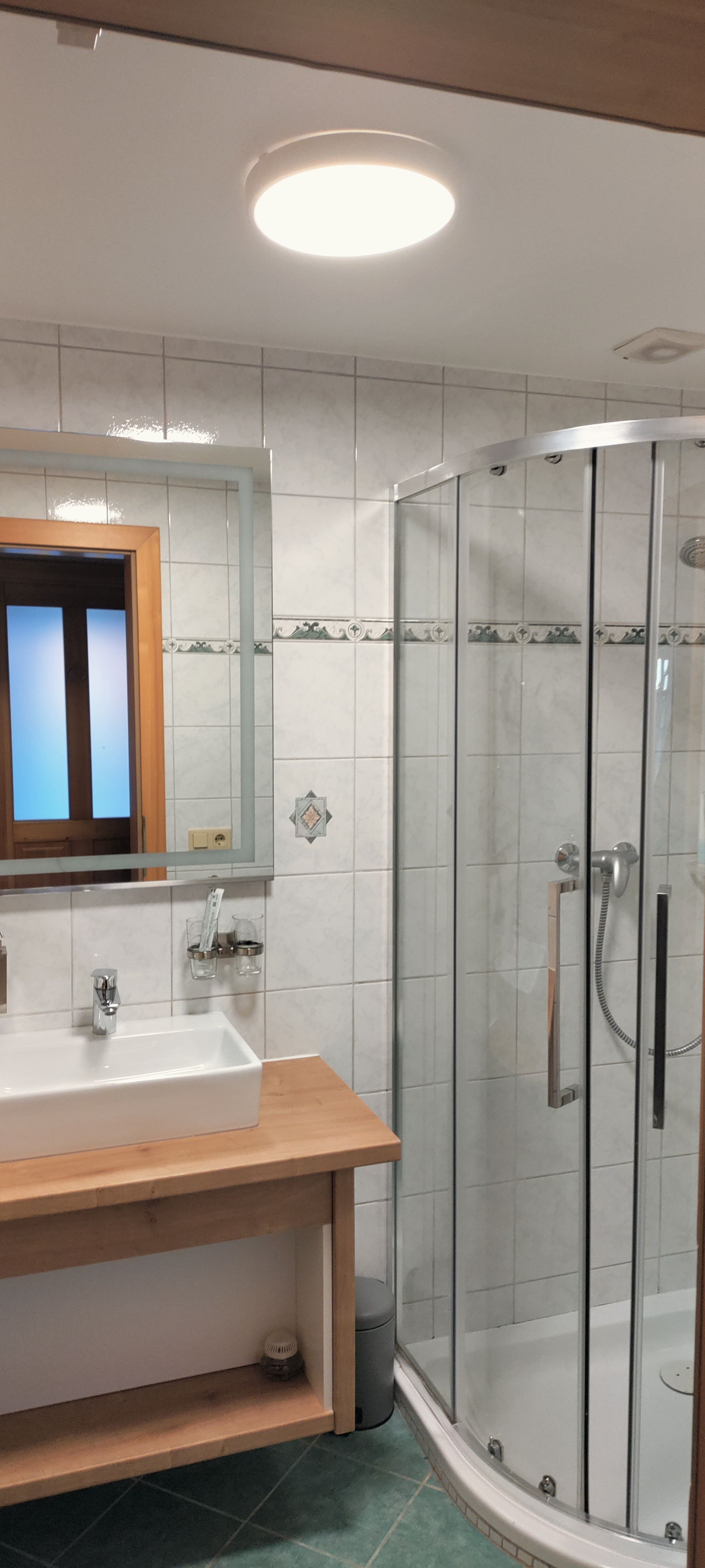 Modern bathroom with shower, washbasin and mirror.