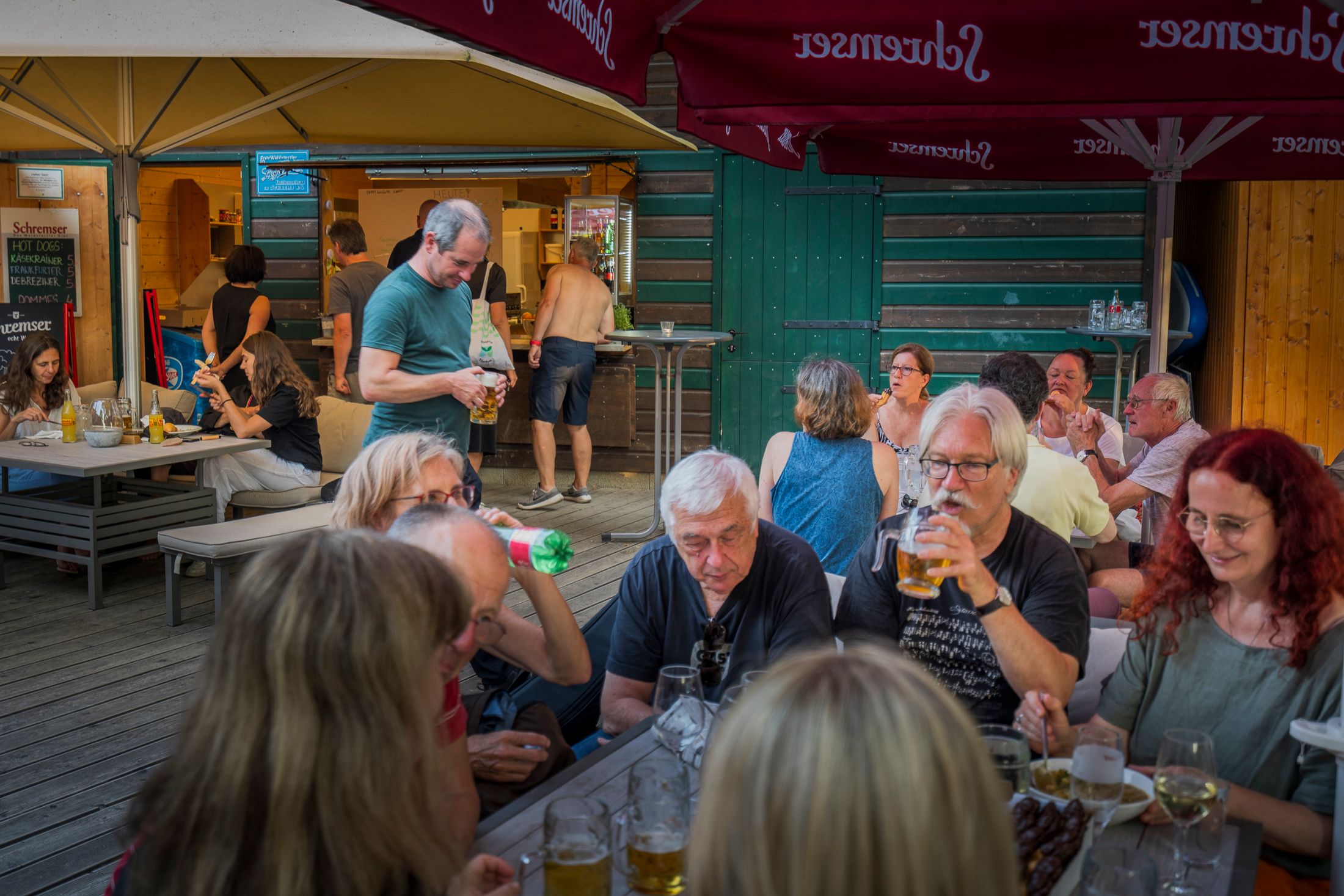 People are sitting at tables in a beer garden, enjoying drinks and snacks.