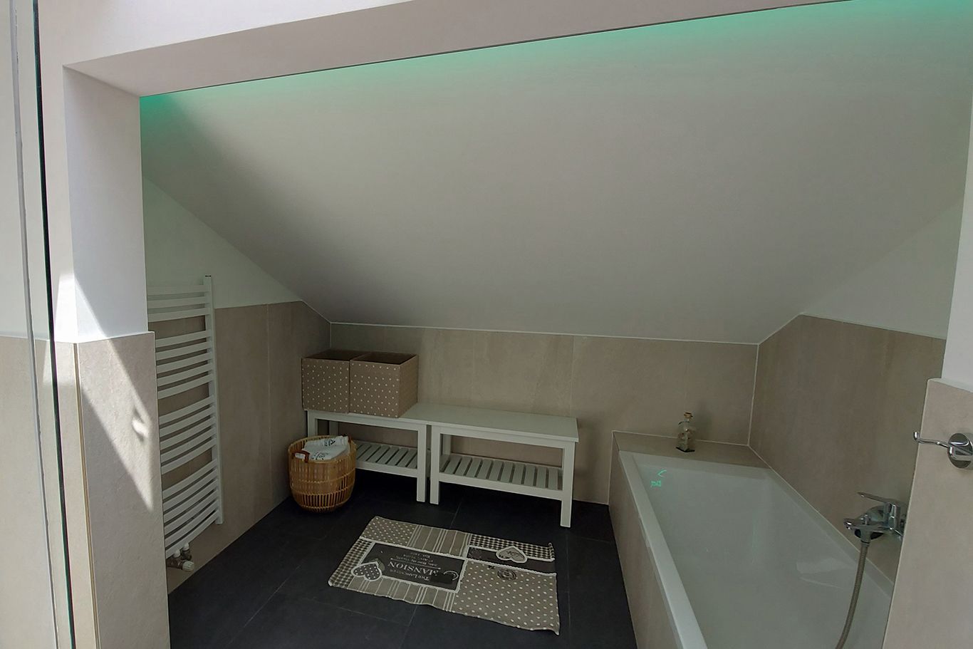 Modern bathroom with bathtub, sloping ceiling, towel rail and decoration.