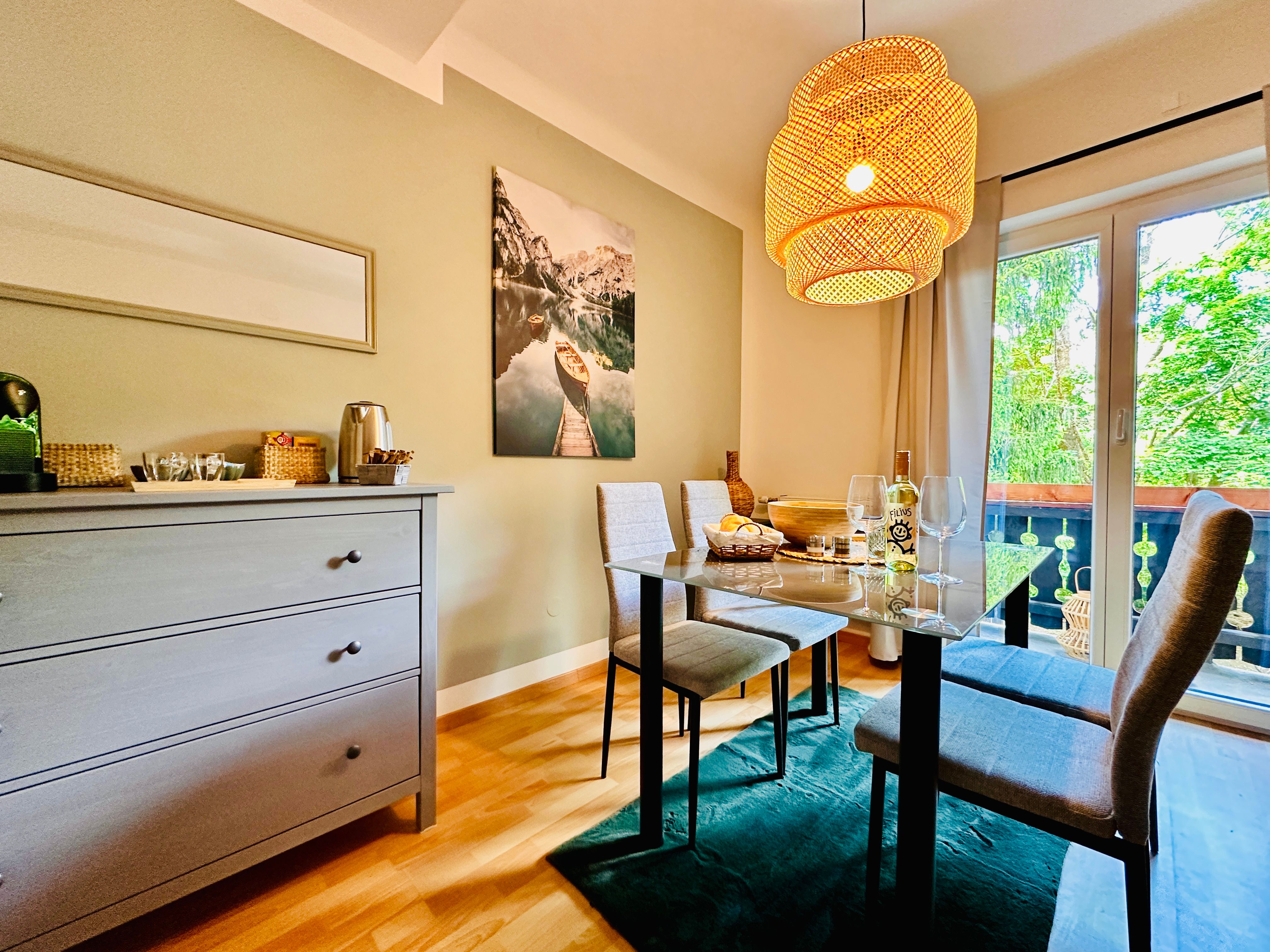 Cozy dining room with table, chairs and hanging lamp, view of balcony and nature.