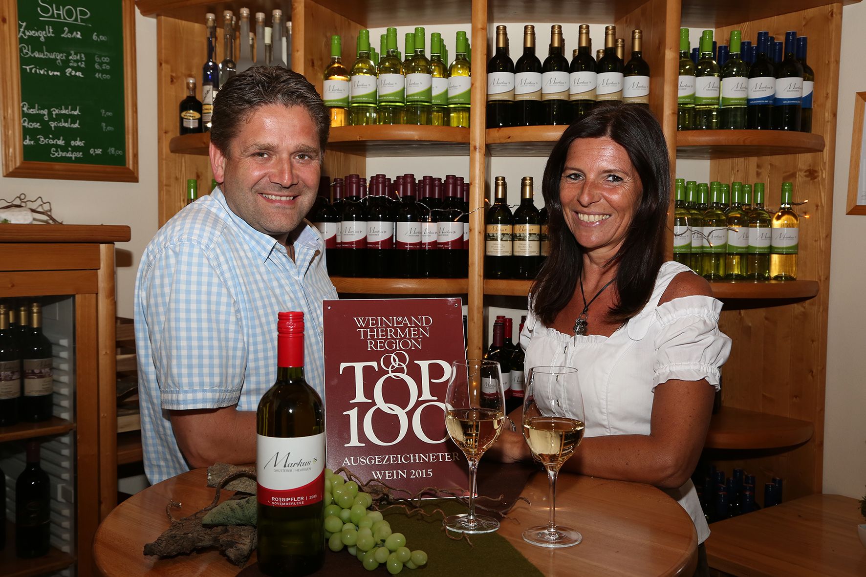 Two people in a wine store with bottles of wine in the background.