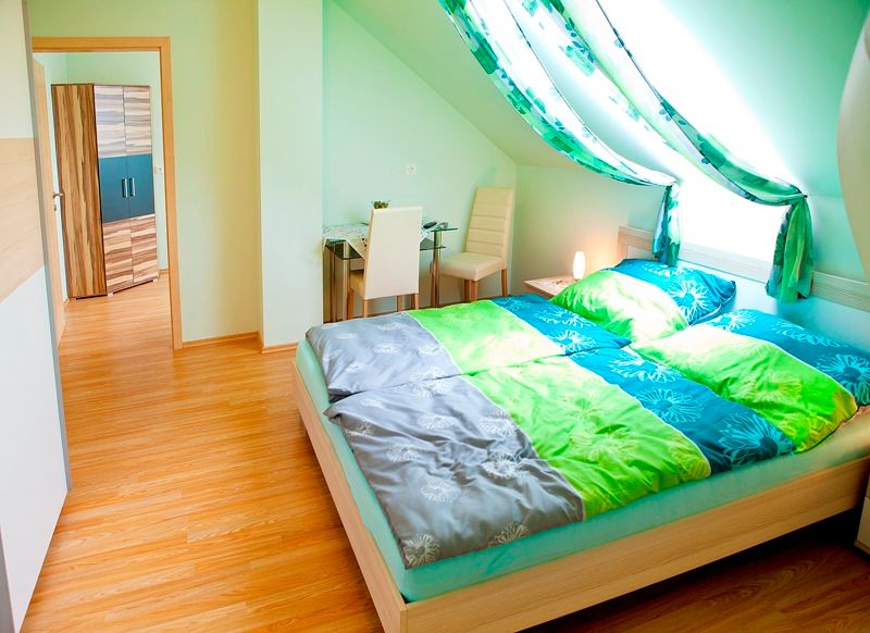 Bright bedroom with sloping ceiling, double bed, desk and chair.