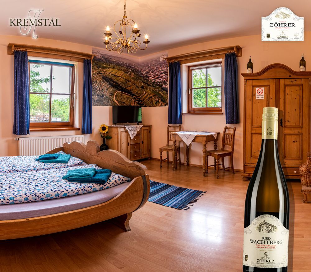 Cozy room with wooden furniture, a barrel bed and a bottle of wine in the foreground.