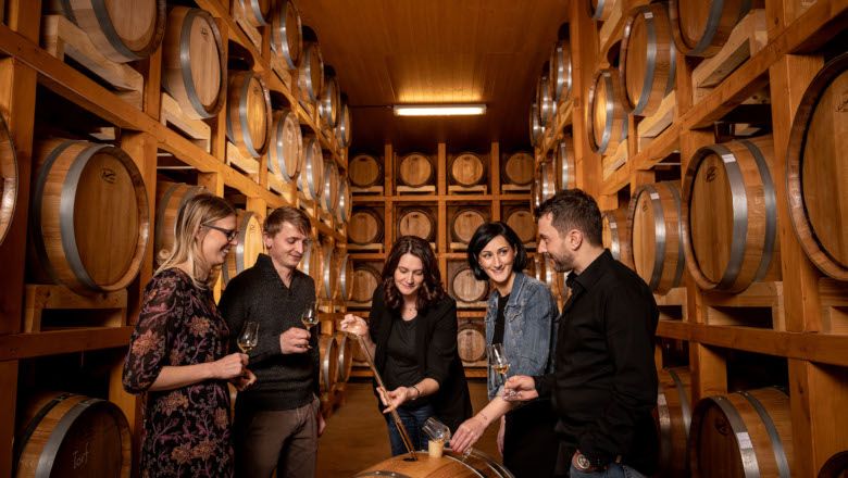 Group of people in a storage room with whisky casks.