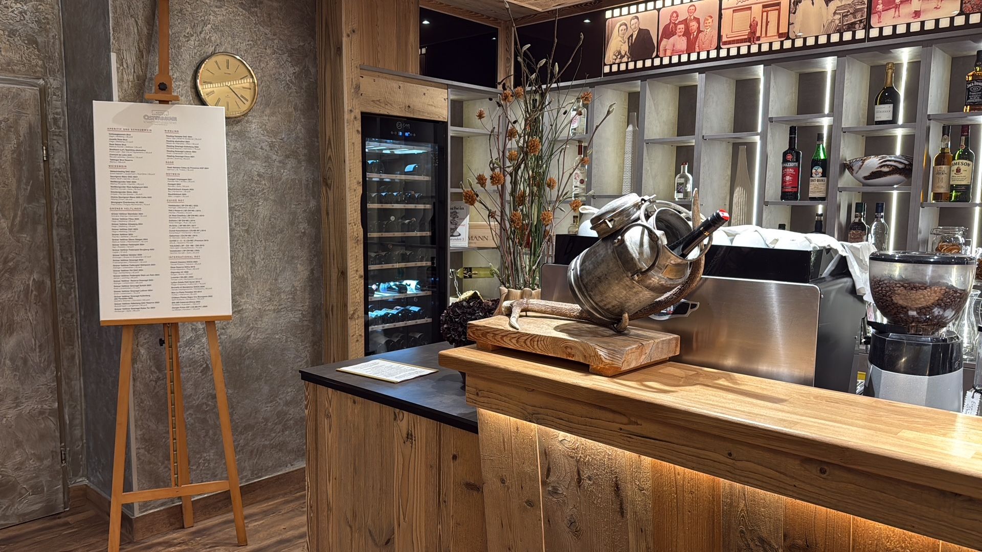 Interior view of a restaurant with rustic counter, wine fridge and menu on easel.