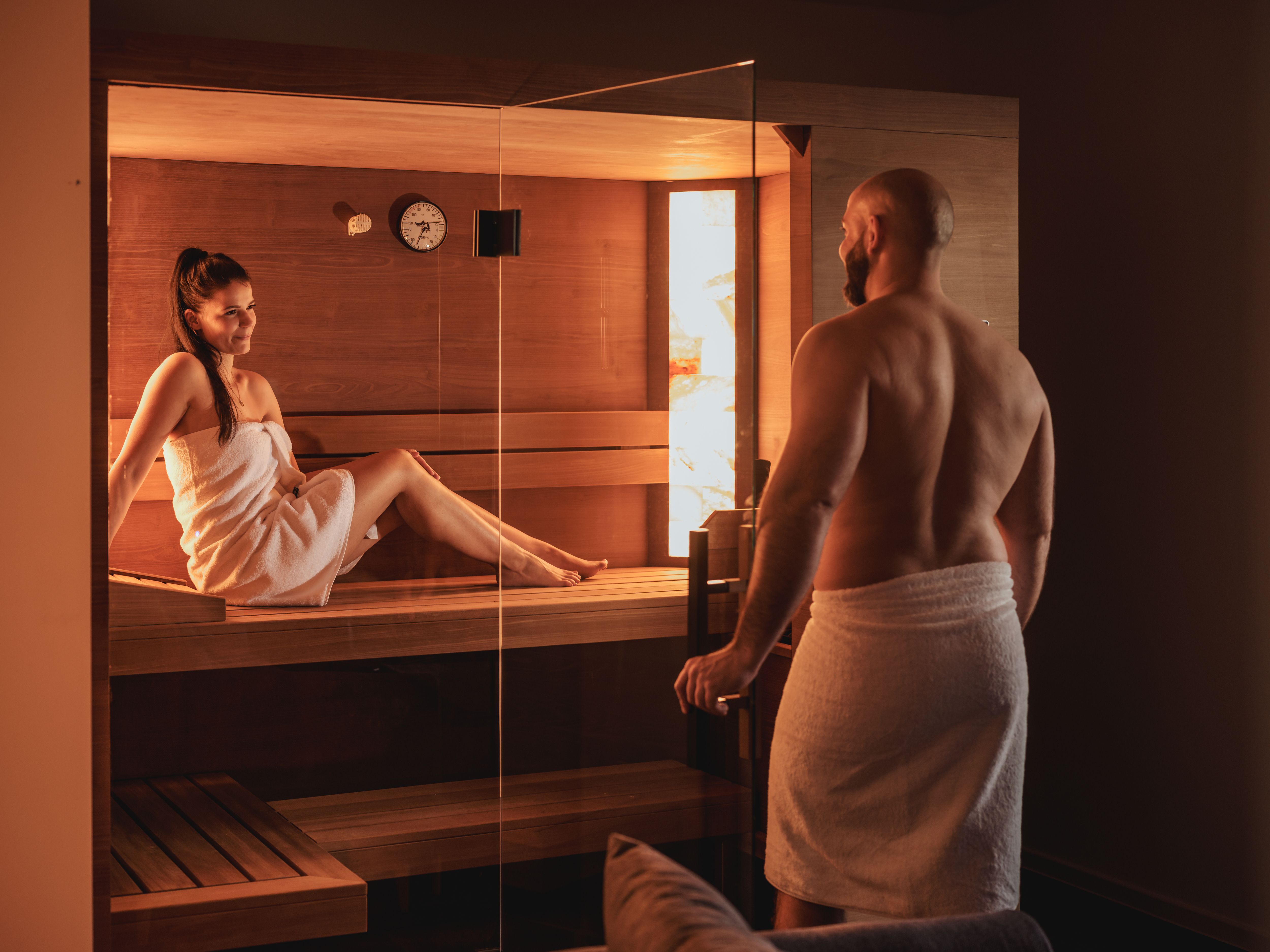 A man and a woman in towels in a sauna.