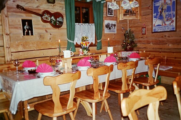 Cozy wooden hut with table setting, candles, decorations and pictures on the walls.