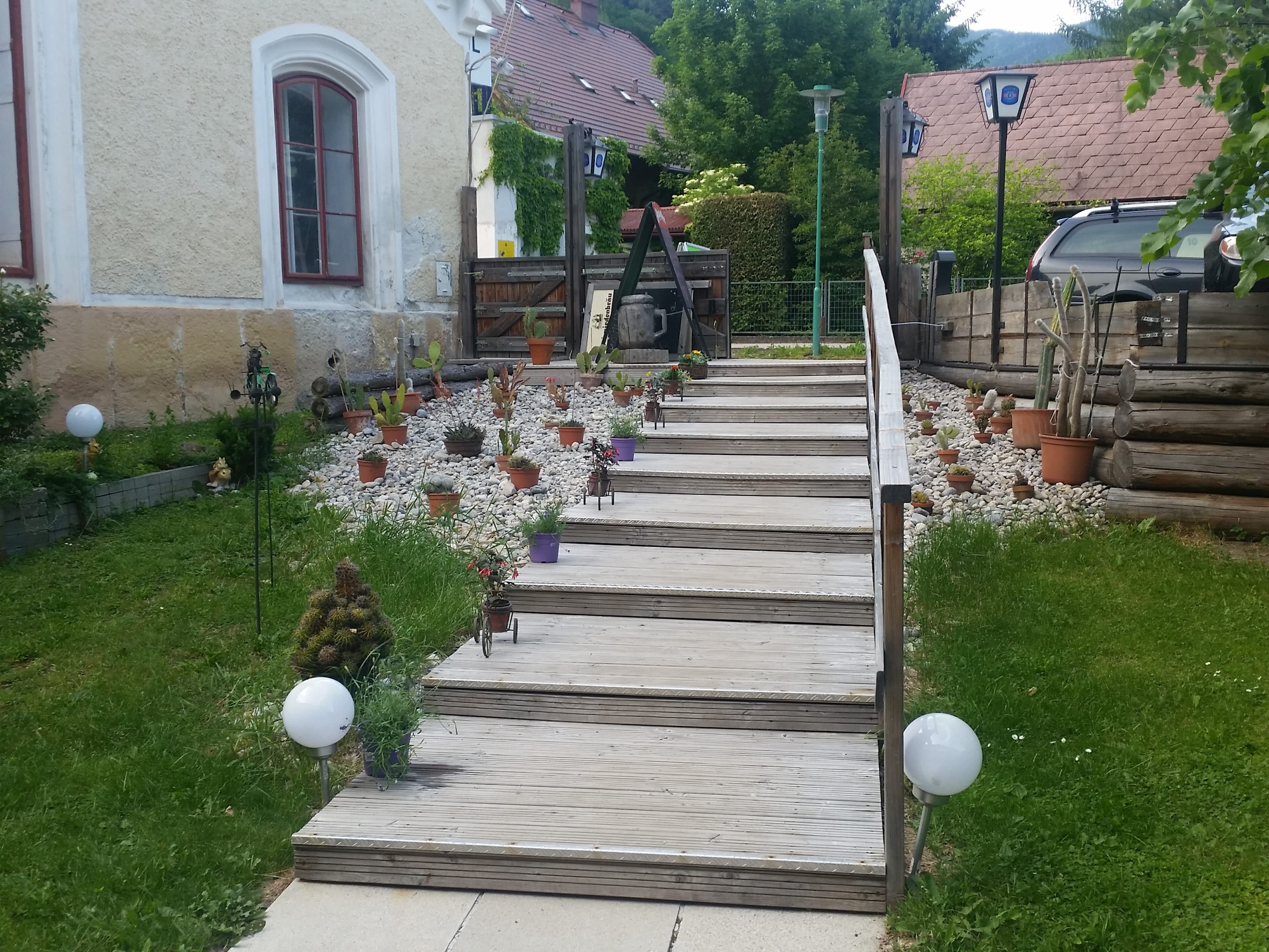 Wooden staircase next to a church with potted plants and pebbles.