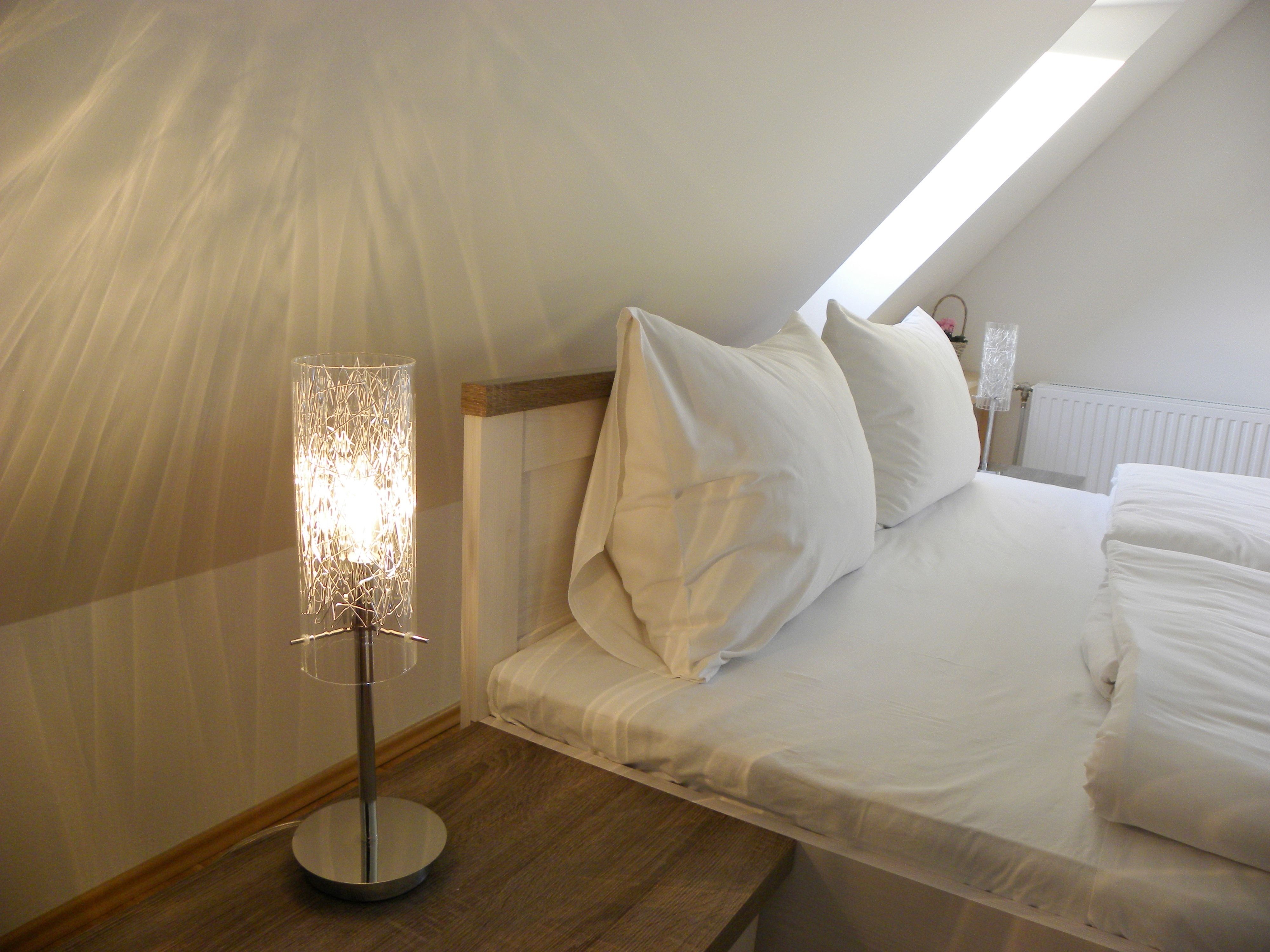 Cozy bedroom with sloping ceiling, bed and bedside lamp.