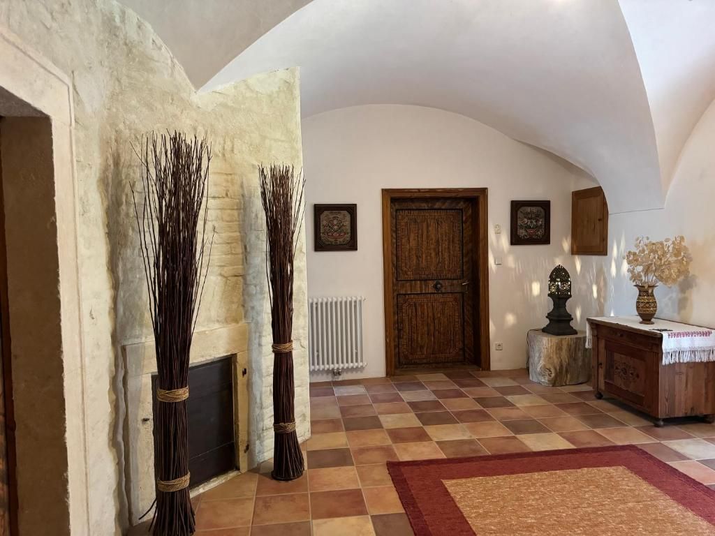 Rustic entrance area with wooden door, decorations and tiled floor.