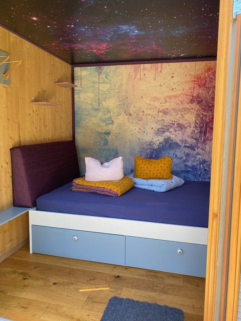 A small, cozy room with a bed and colorful pillows.