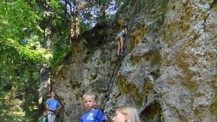 Children climbing on a rock face in the forest.