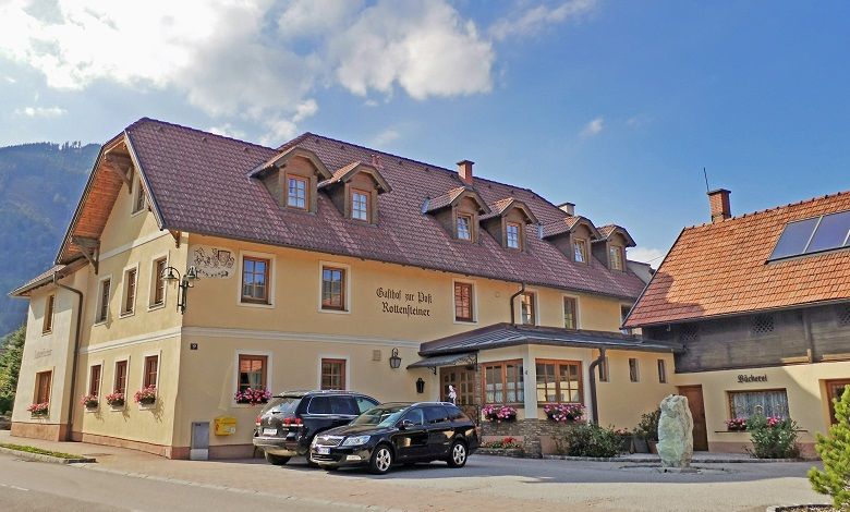 A traditional inn with a bakery and parked cars in front of it.