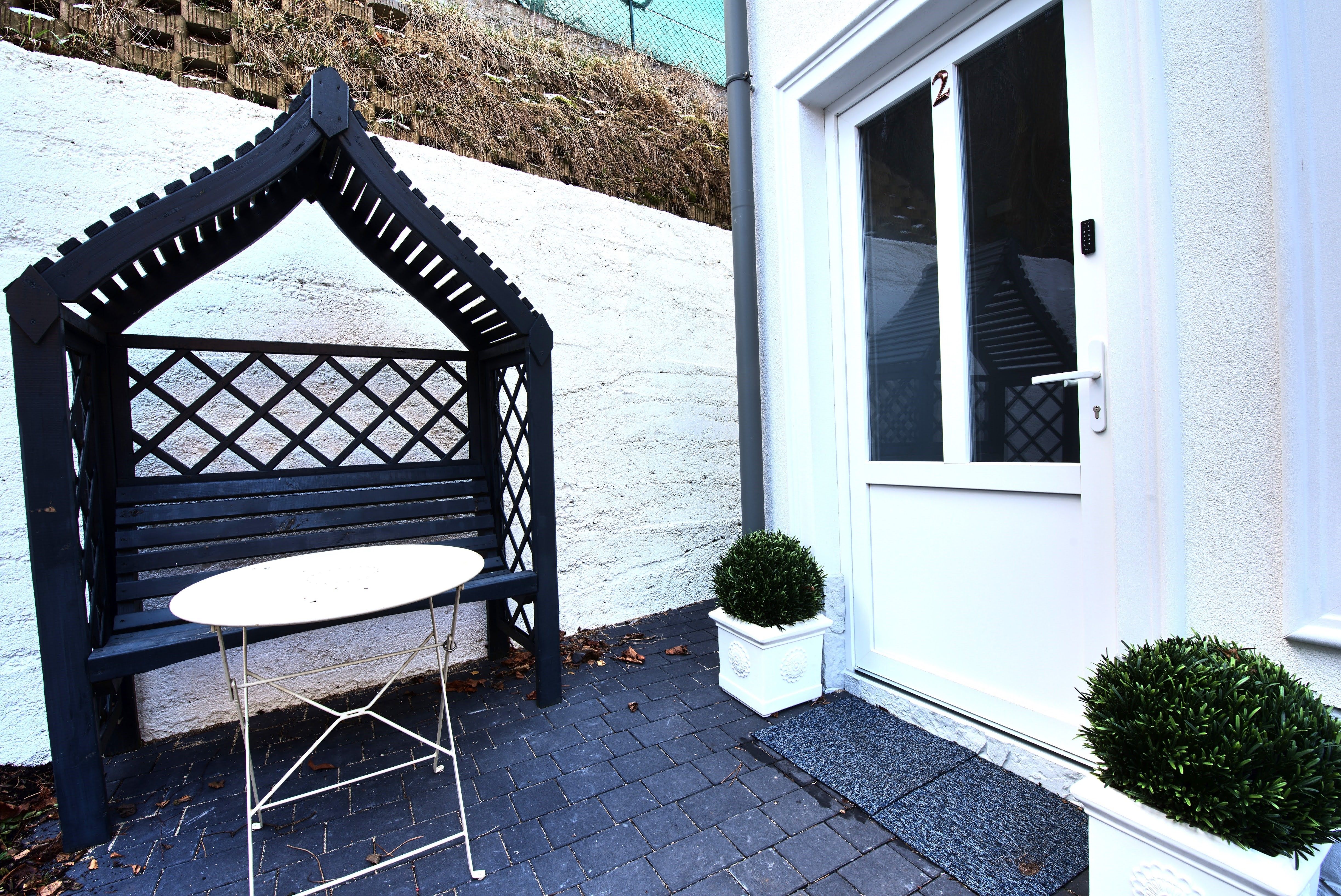 Entrance area with white door, black bench with canopy and small table.