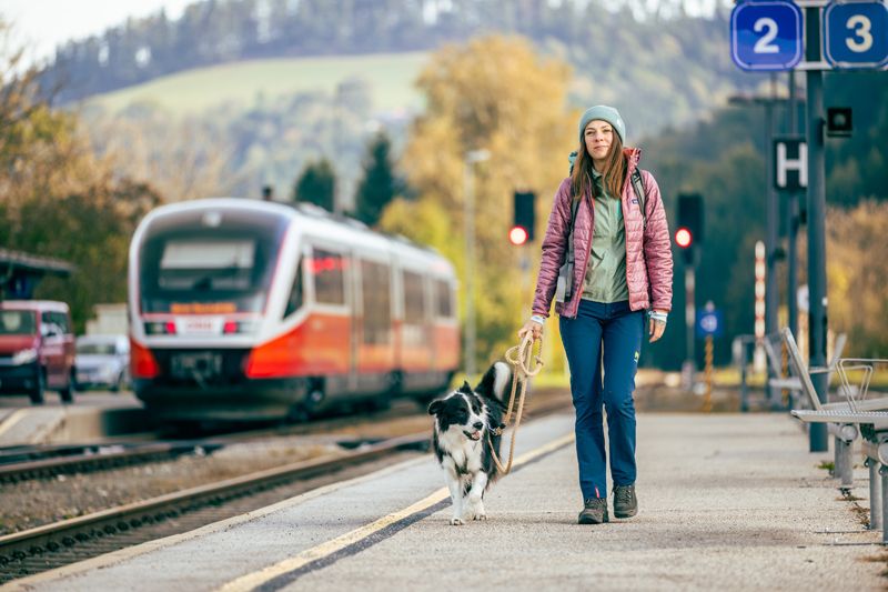 Woman with dog at Aspang station, train in the background.