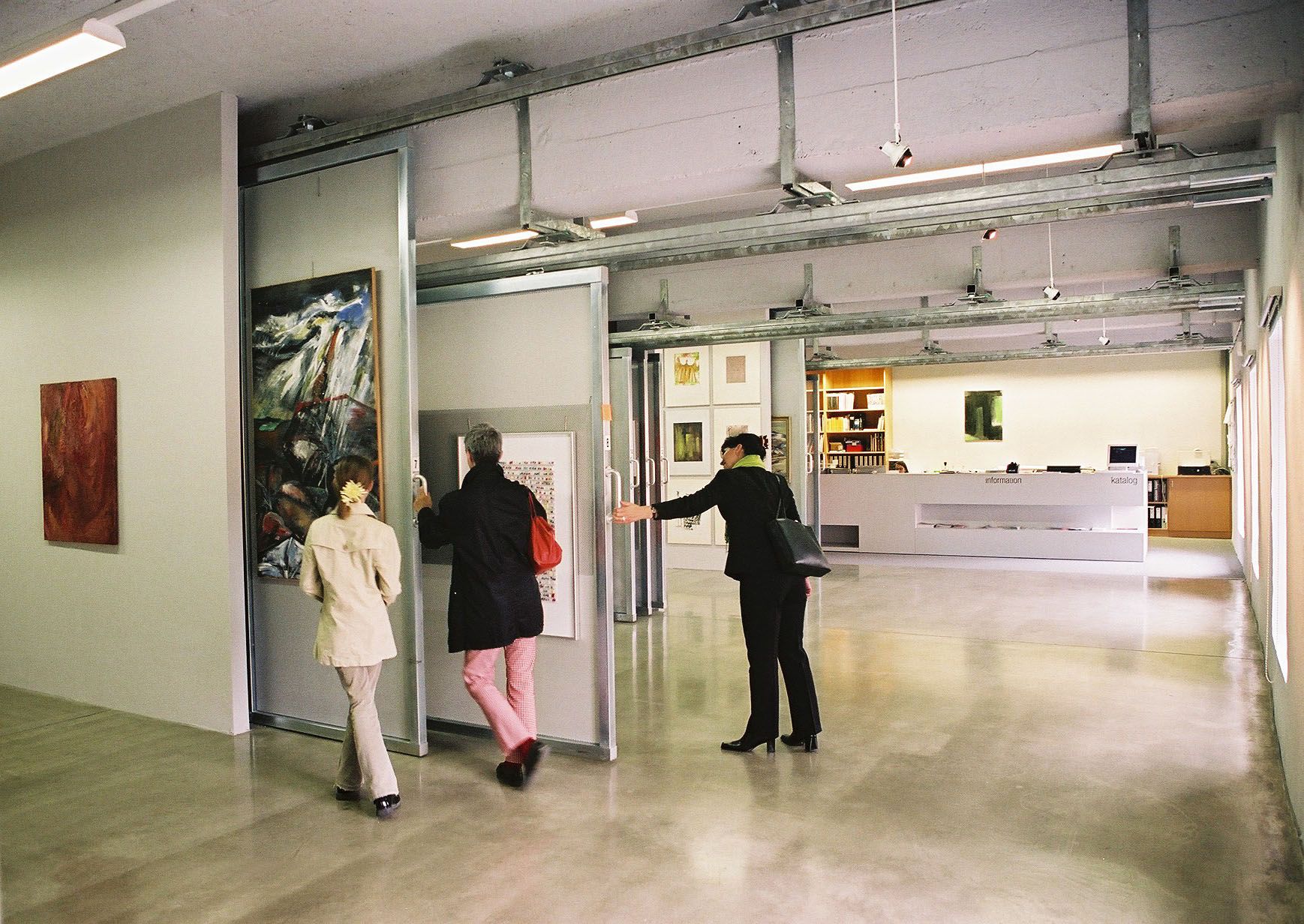 Interior view of an art library with people looking at works of art.