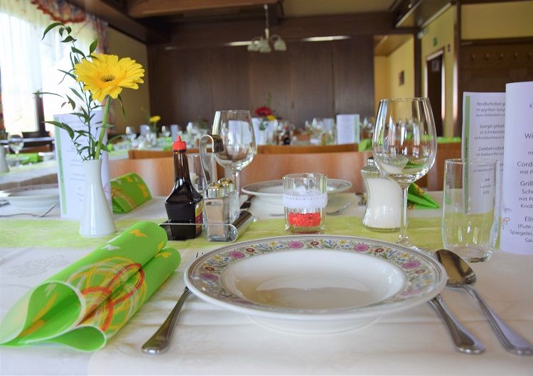 Festively laid table in a hall with flowers, crockery and glasses.